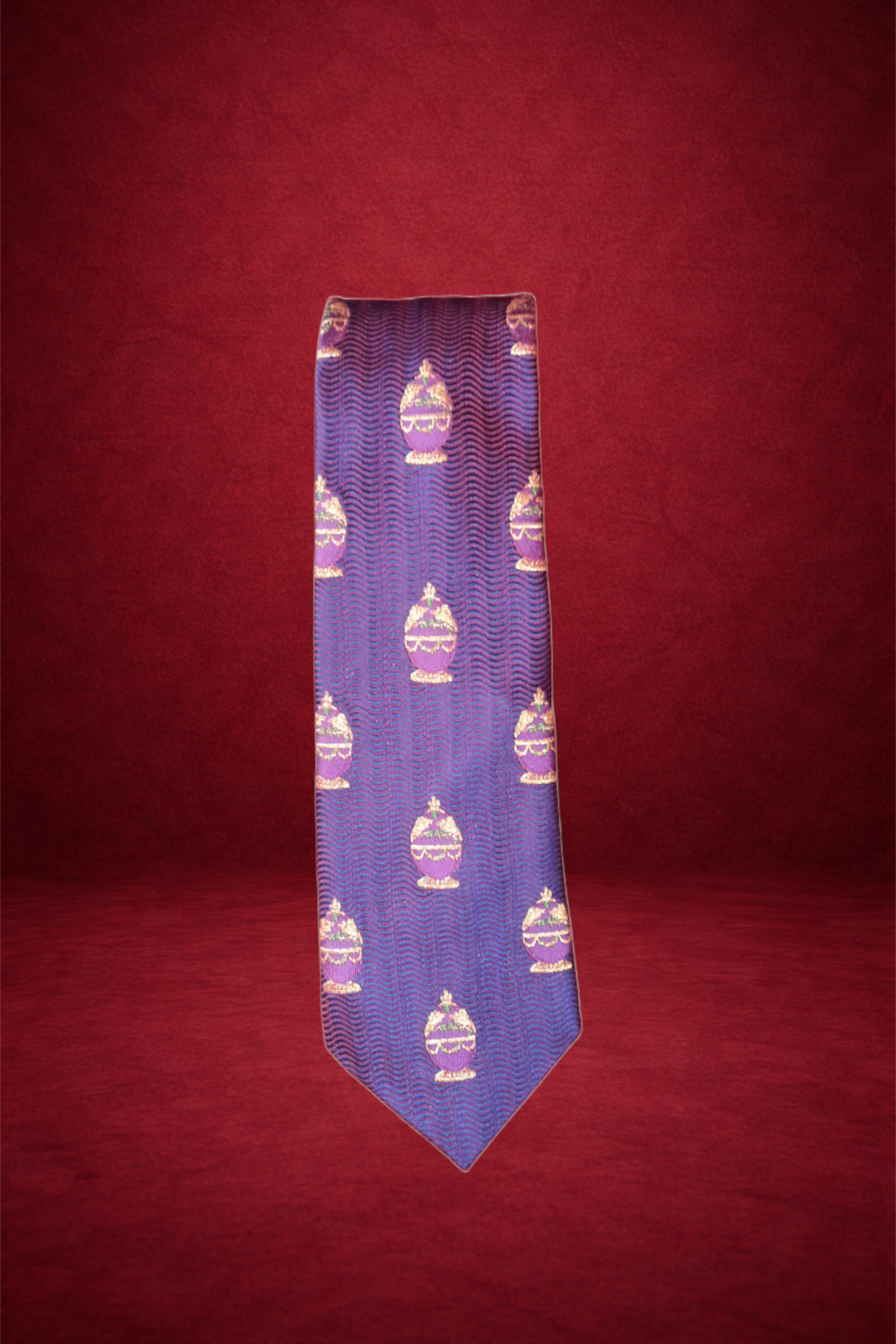 Purple necktie with repeating pattern of decorated cake in gold and pink, against a red background.