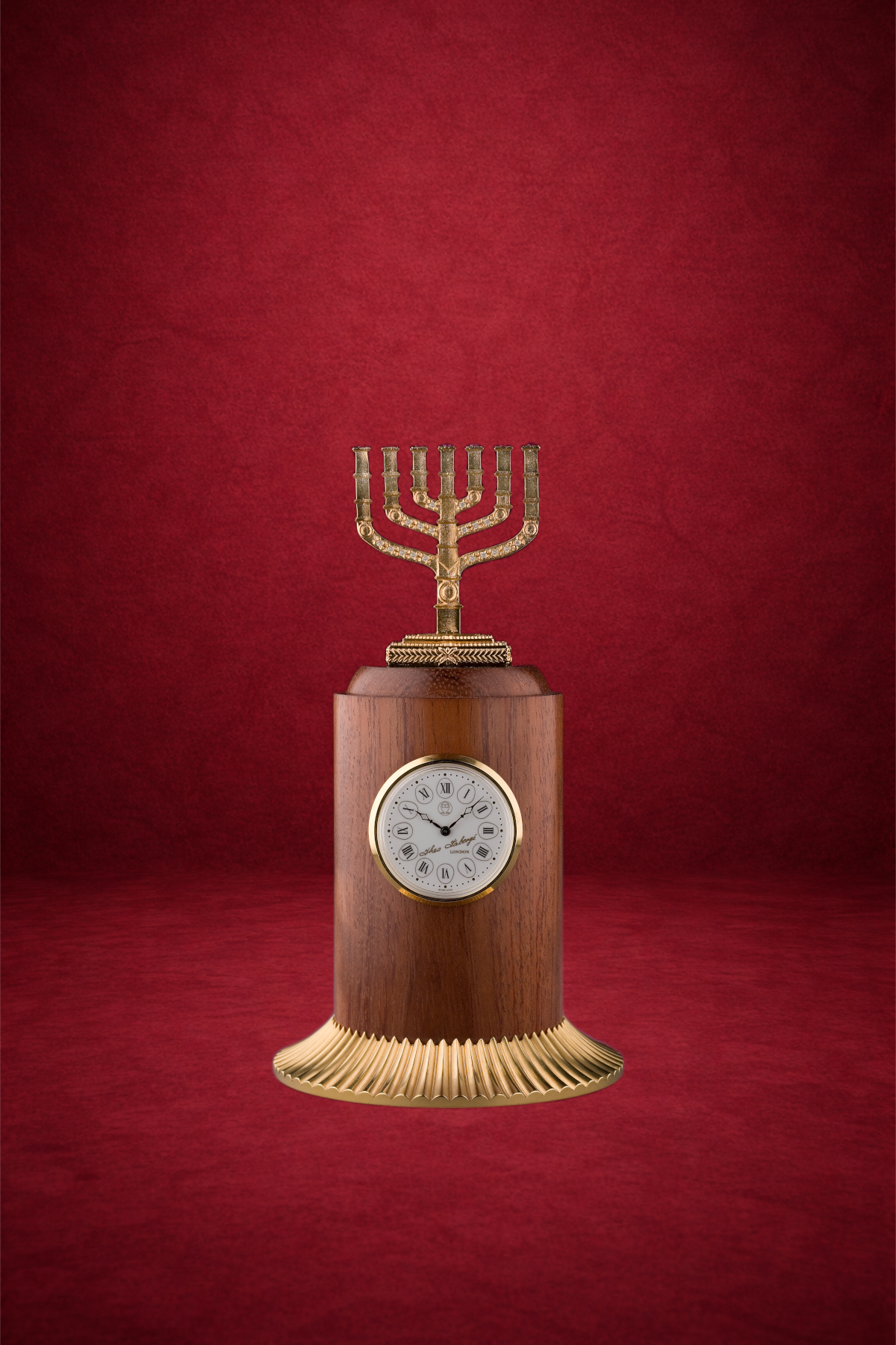 A decorative clock with a menorah on top, made of wood, with a brass base and accents, set against a red background.