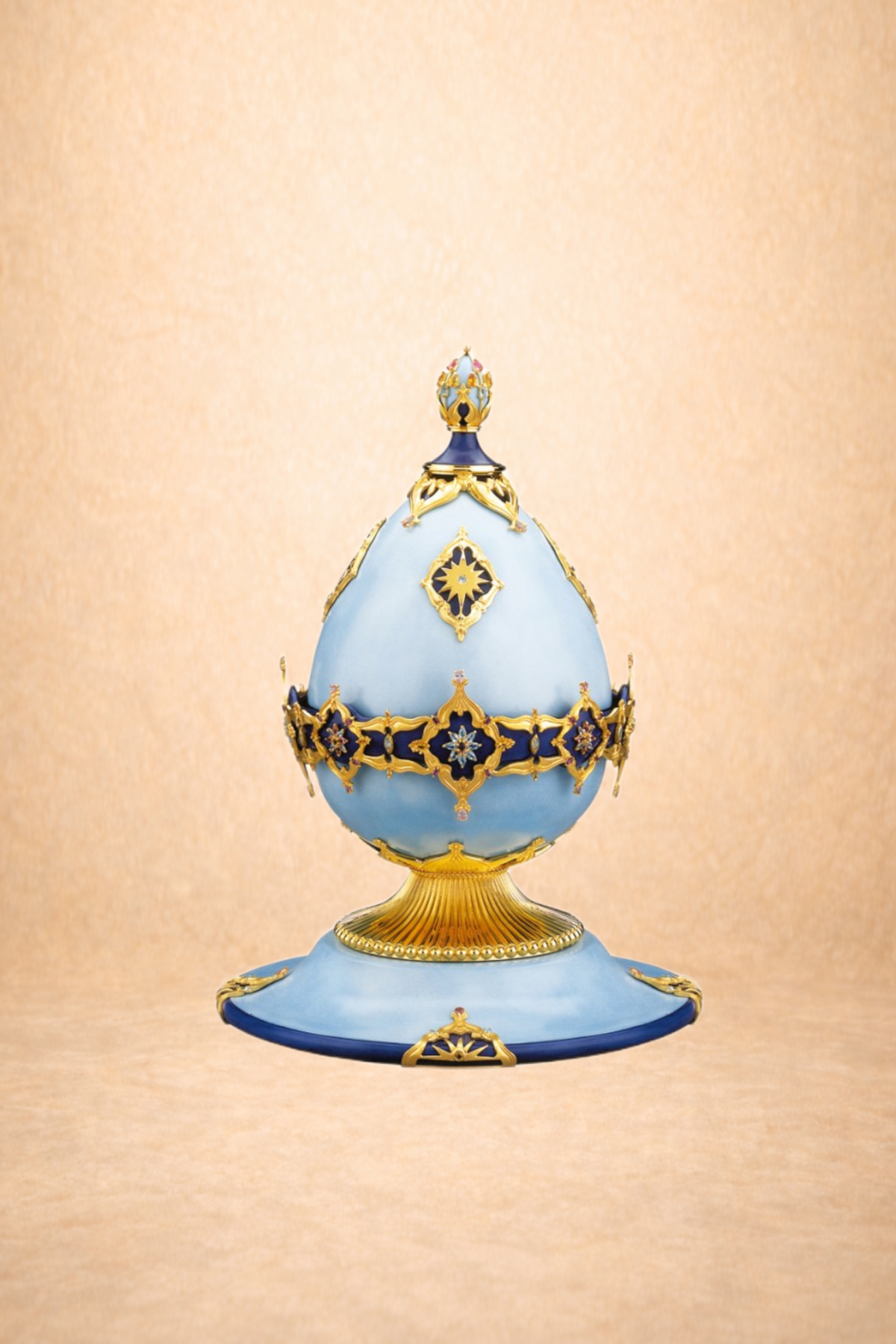 Ornate decorative egg-shaped object with blue and gold details, set against a light peach background.