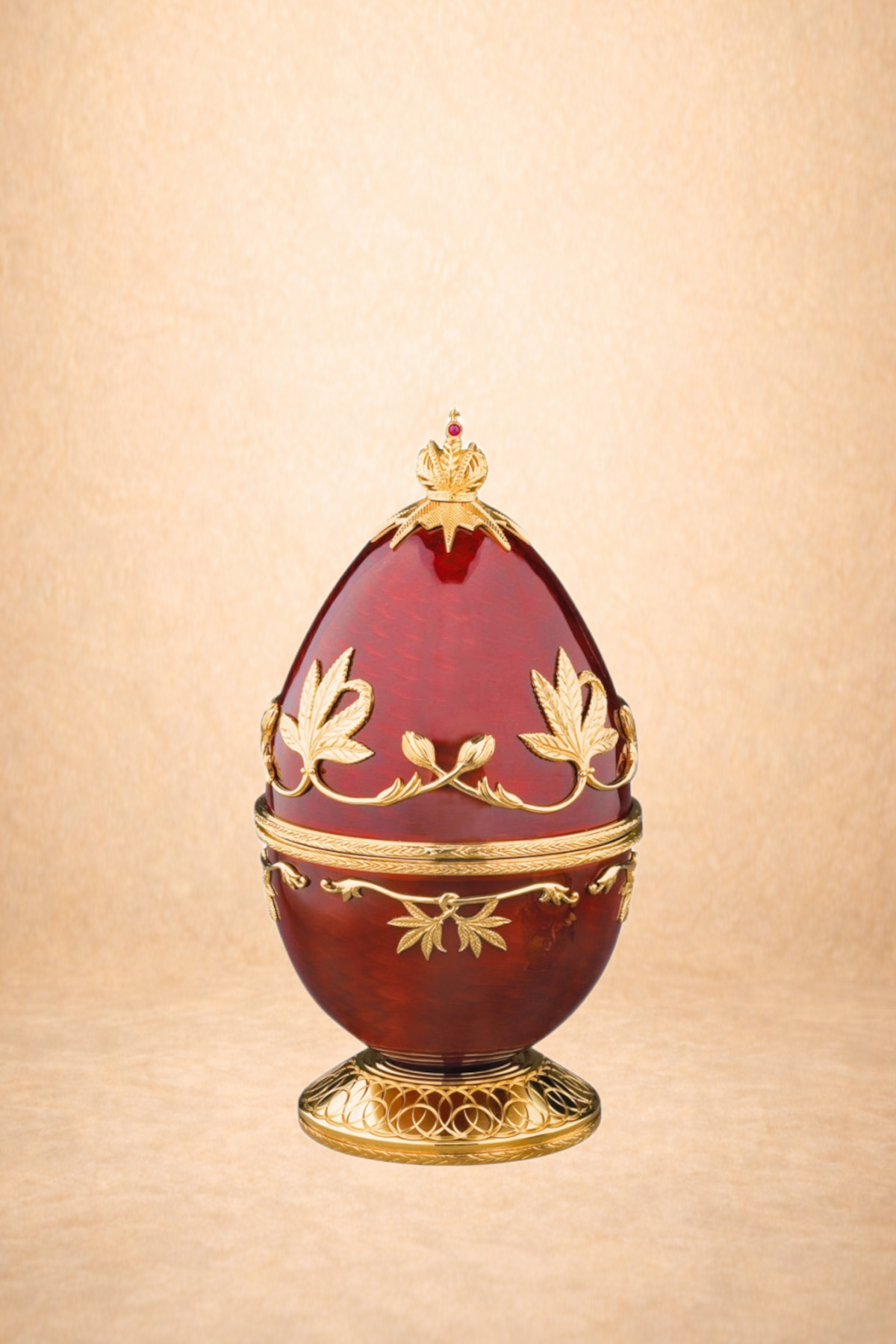 Ornate red and gold decorative egg with floral and crown details, mounted on a gold stand.