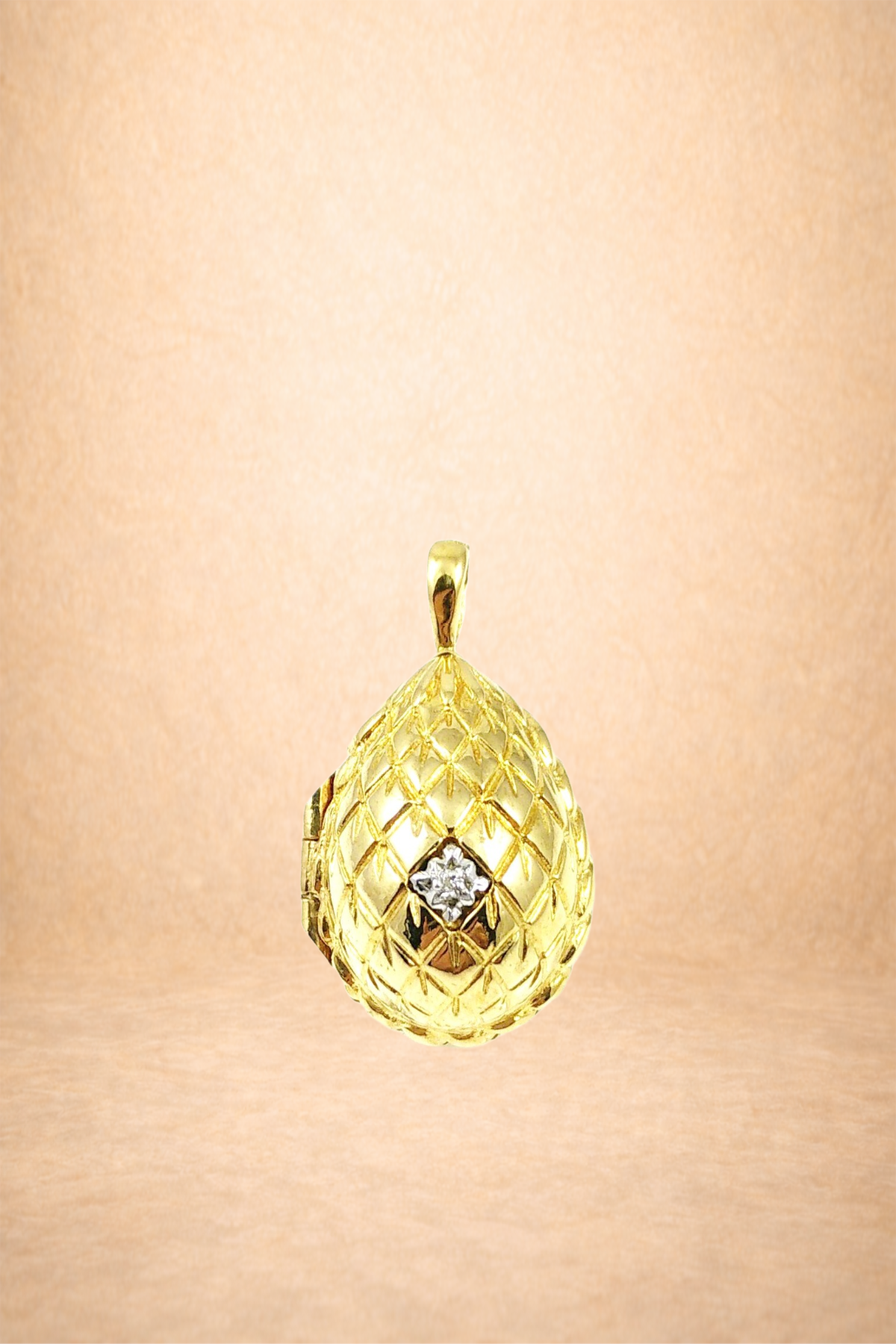Gold pendant jewelry with diamond accent, hanging against a neutral background.