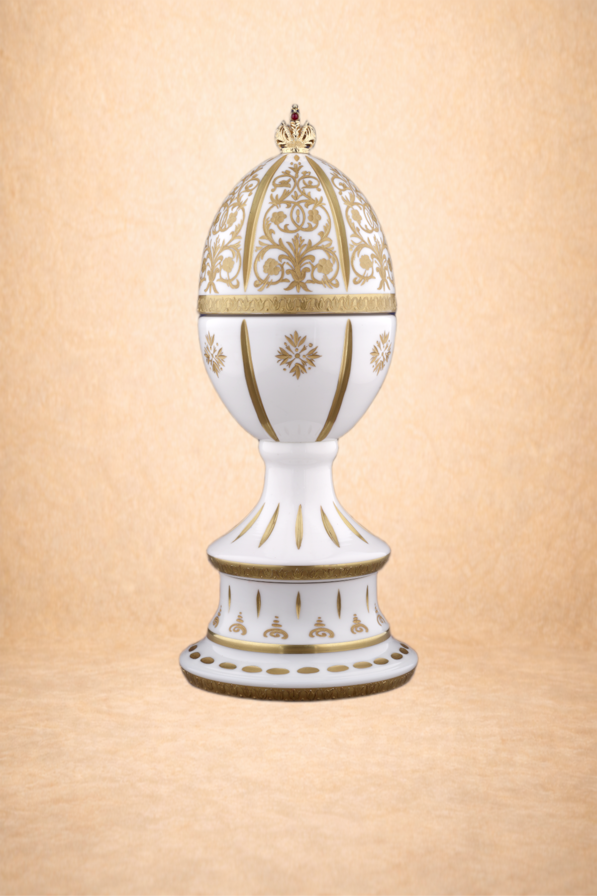 Decorative, ornate egg-shaped container with gold floral patterns and a small crown on top, displayed on a stand with matching design.