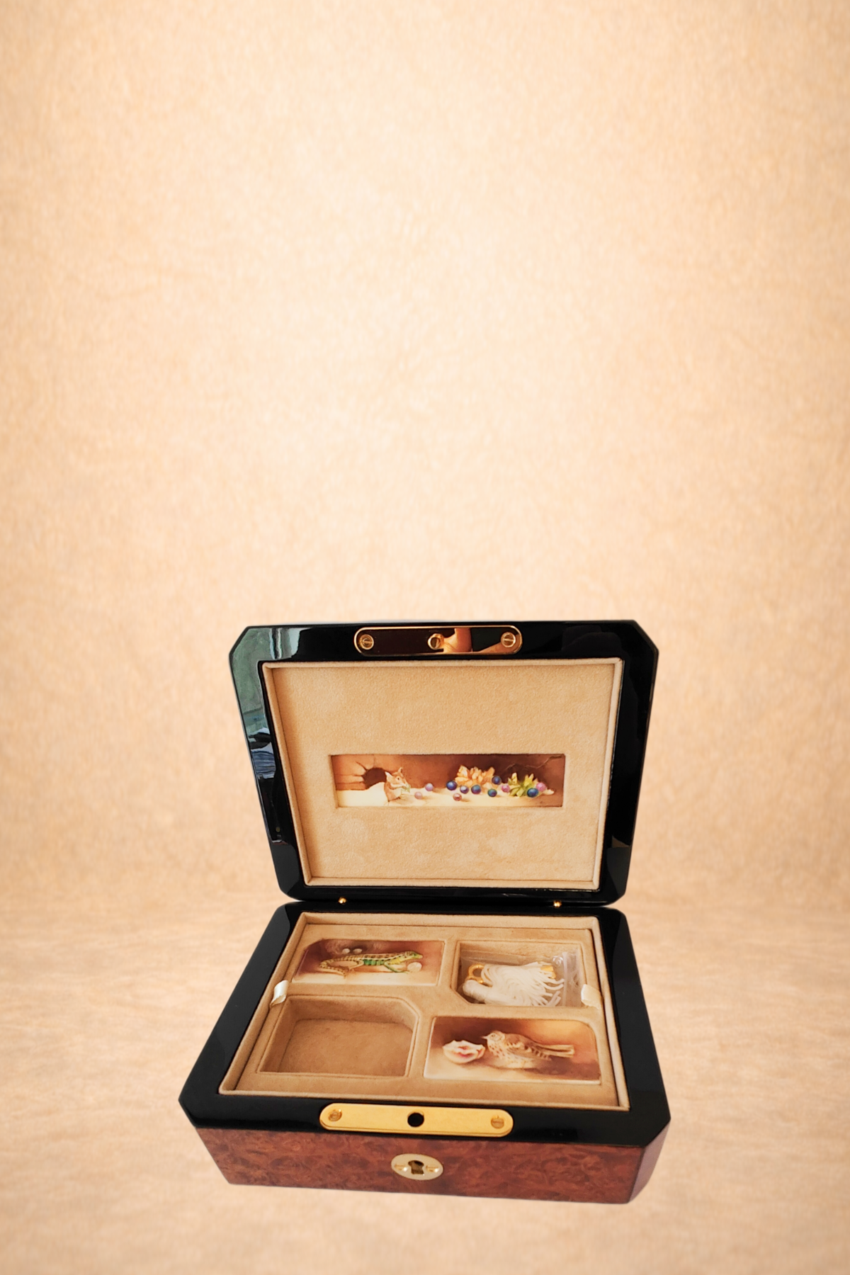 An open jewelry box with a velvet lining displaying small figurines and jewelry inside, against a beige background.