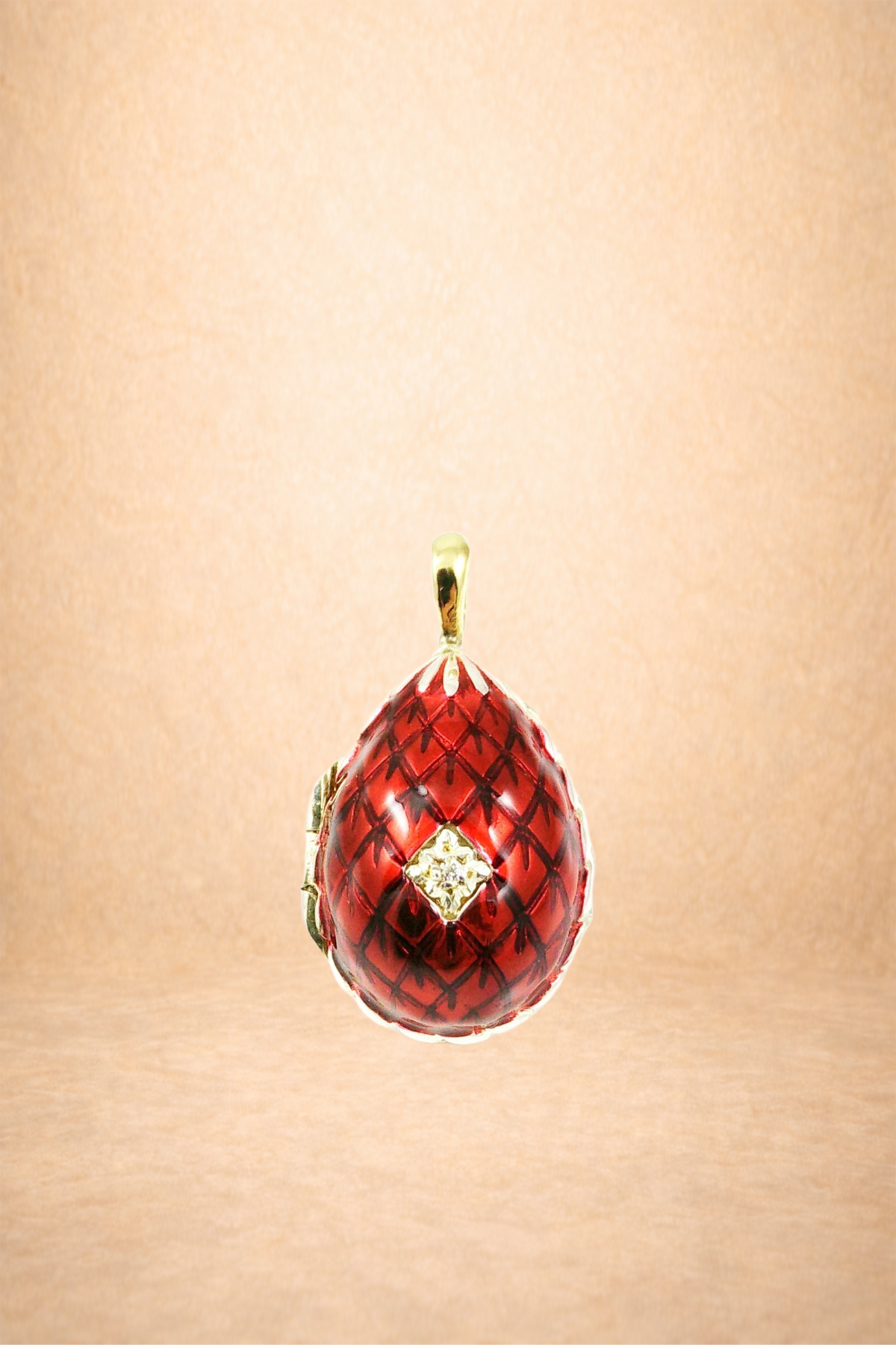 Gold and red filigree pendant with a small diamond cluster in the center, hanging against a beige background.