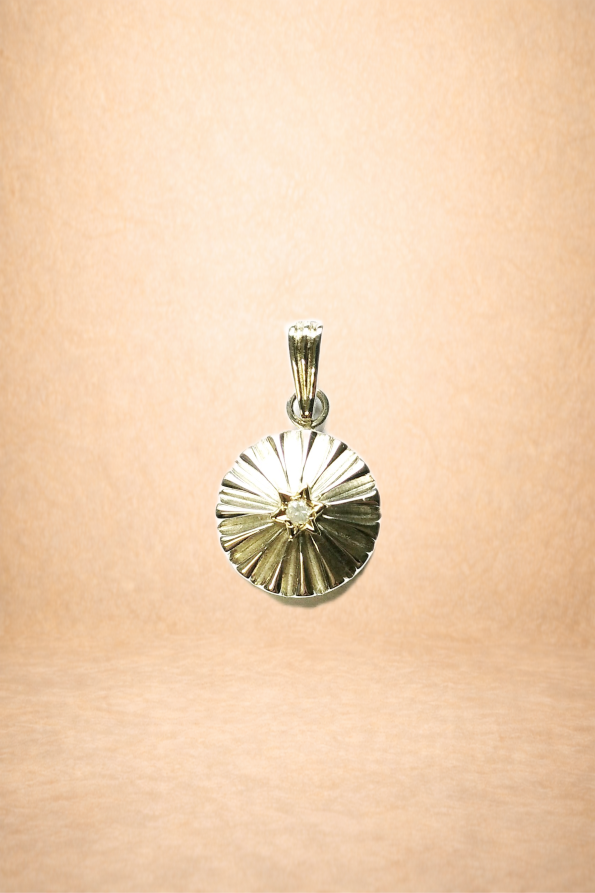 Silver pendant necklace with a circular, ridged design and a small central gemstone, shown against a plain background.