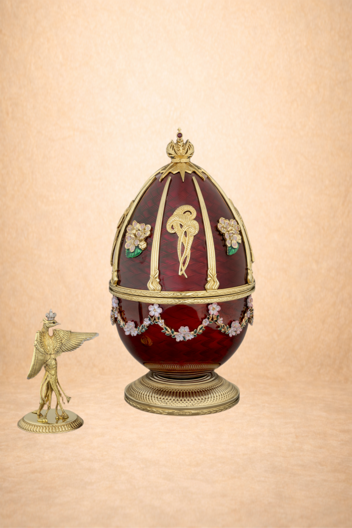 A decorative egg with gold accents, floral decorations, and a crown on top, set against a beige background.