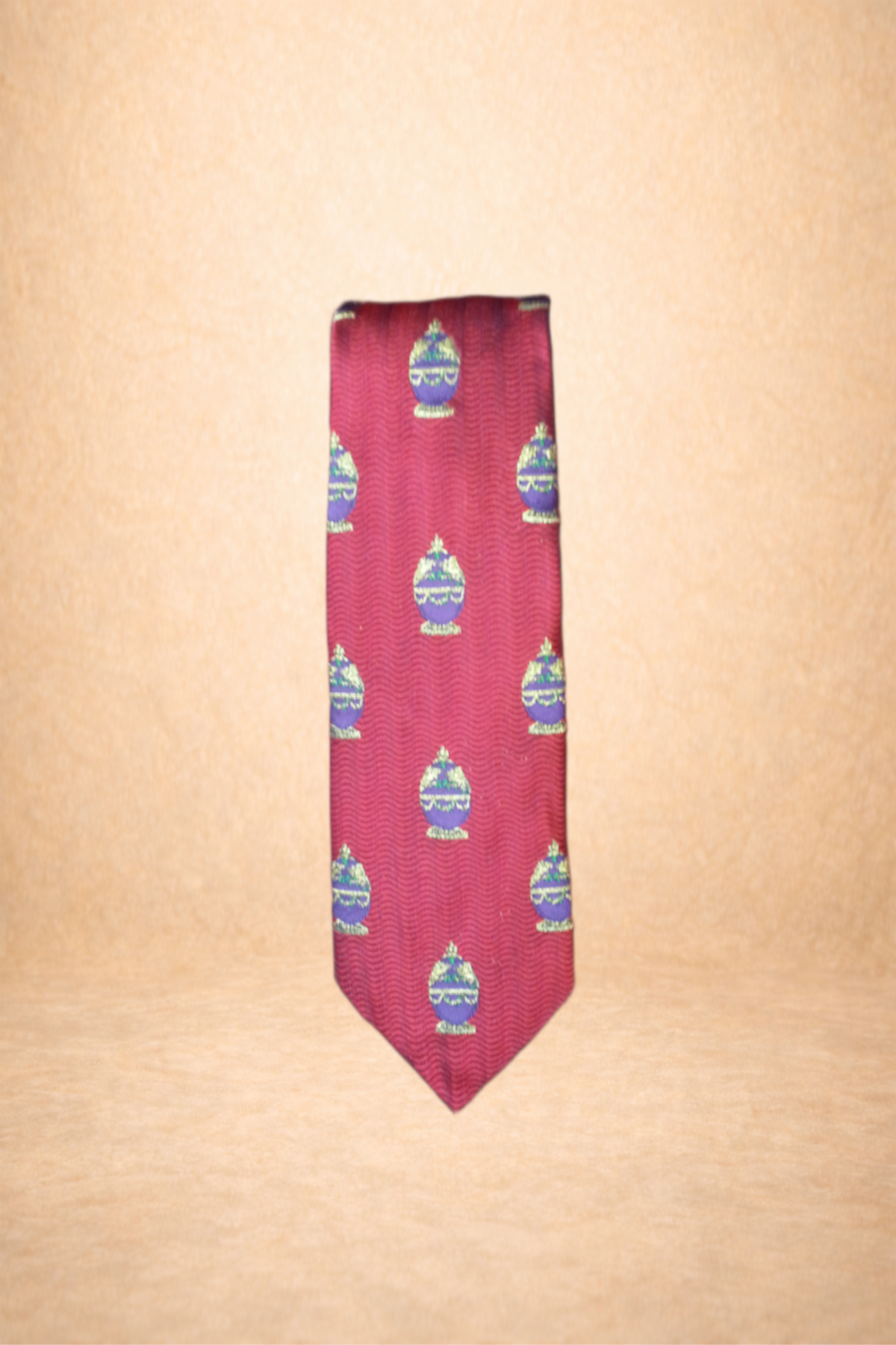 A red necktie with a repeated pattern of green and purple decorative ornaments.