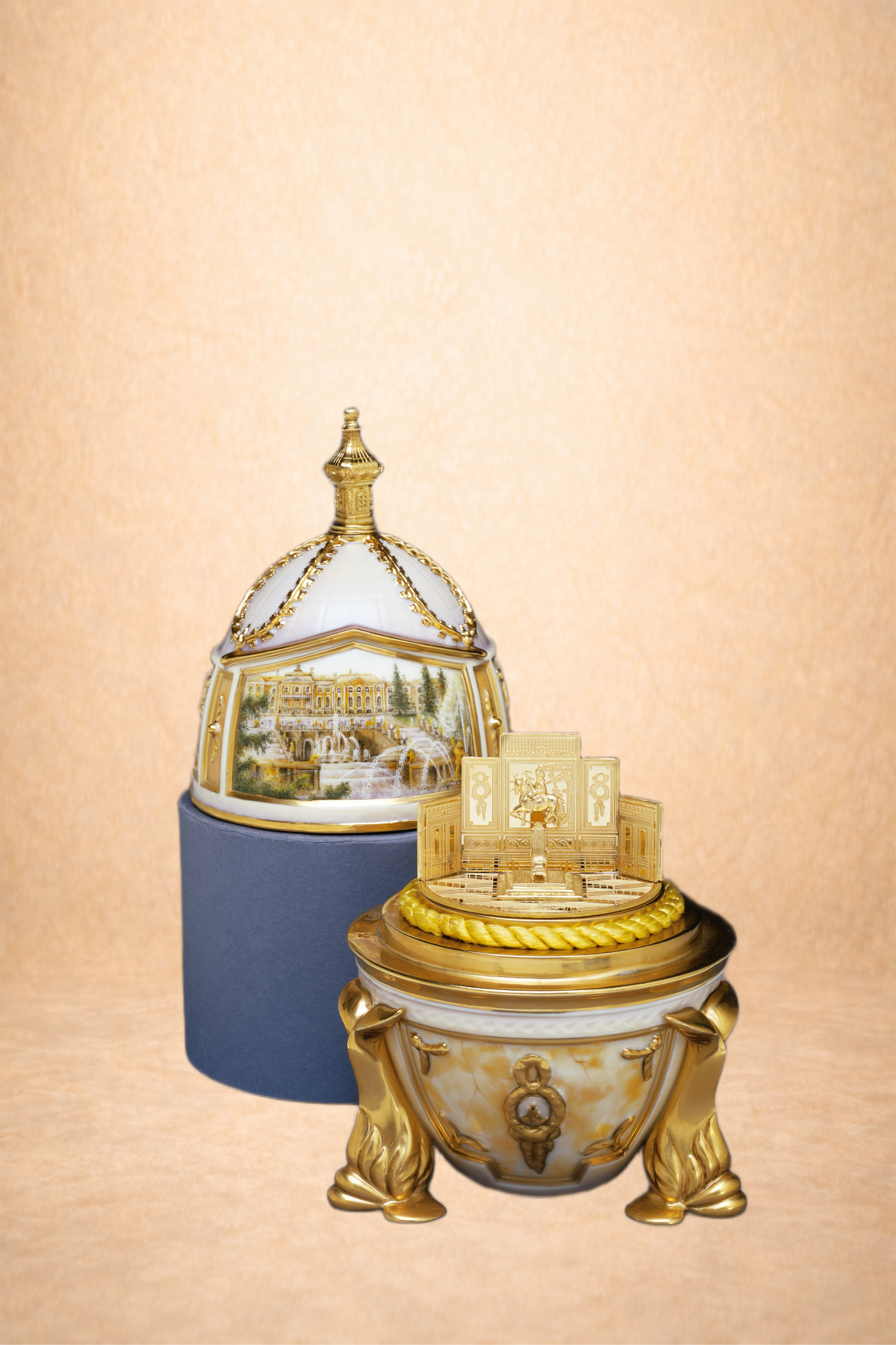 Decorative porcelain and gold collectible items, including a small fountain and a domed house, displayed on a blue and white stand against a beige background.