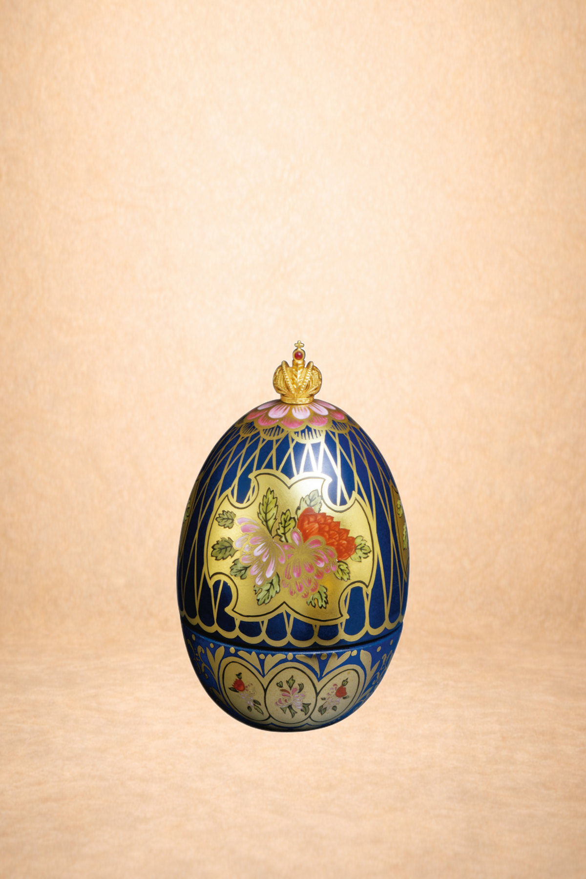 Decorative Easter egg with floral patterns, topped with a small golden crown on a peach background.