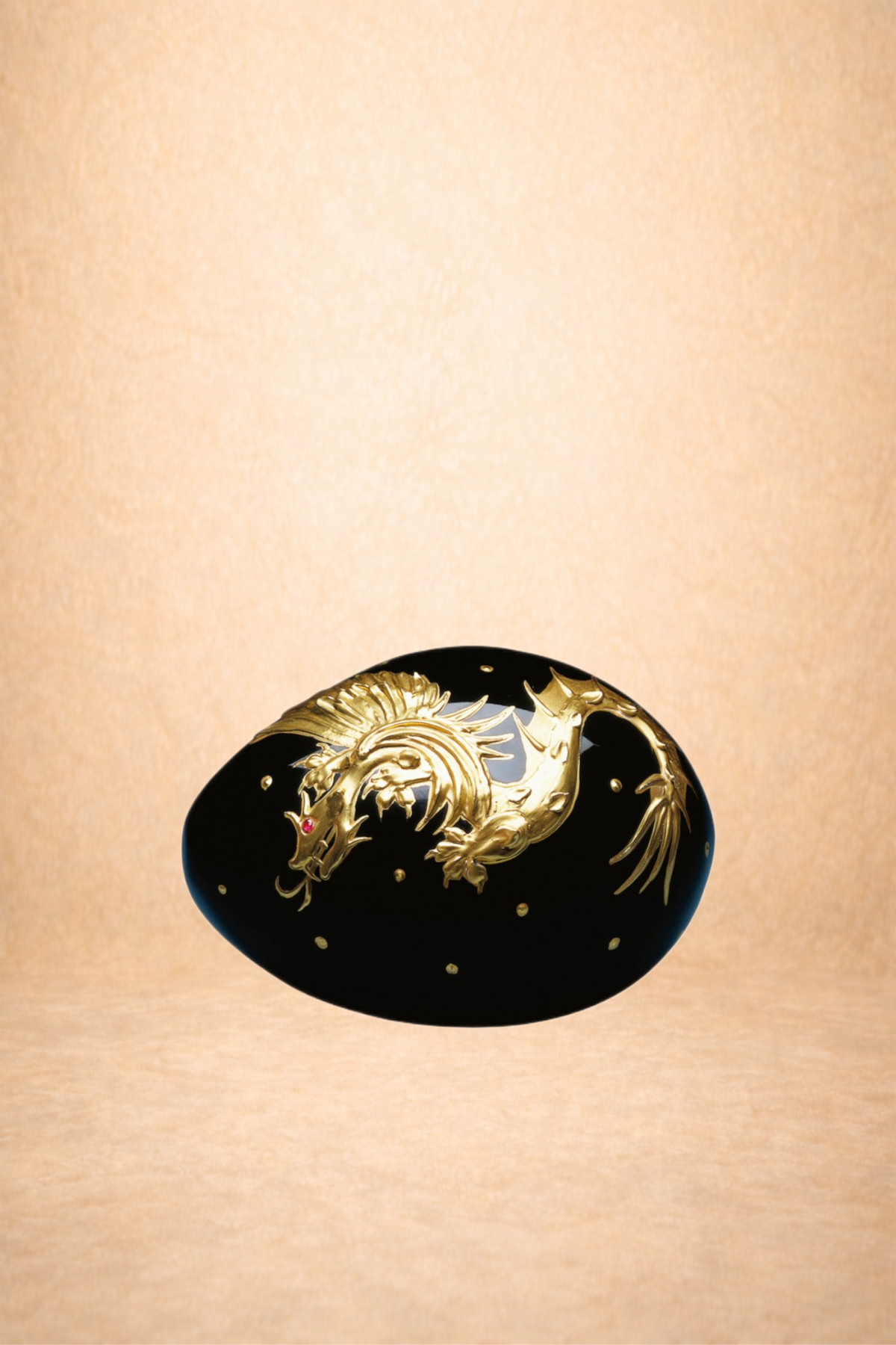 Black decorative object with gold dragon design and small gold dots on a neutral background.