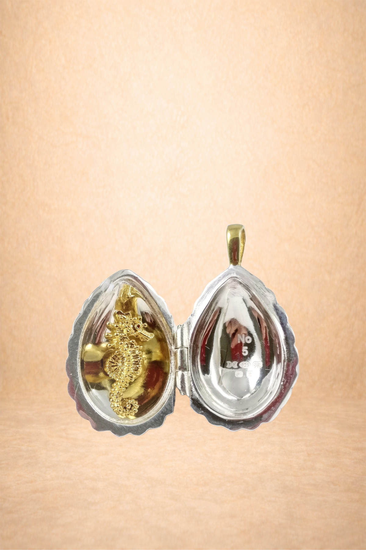 A small, heart-shaped metallic container with a seahorse ornament inside, displayed against a plain background.