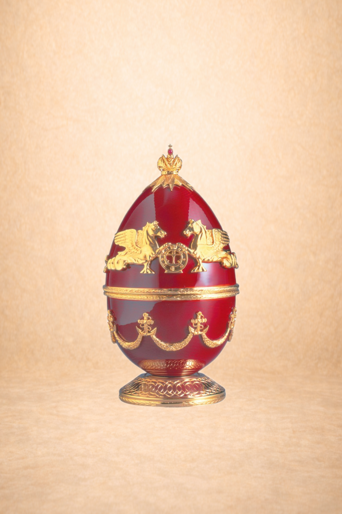 A decorative red egg with gold embellishments and a gold stand, featuring gold lions and heraldic symbols.