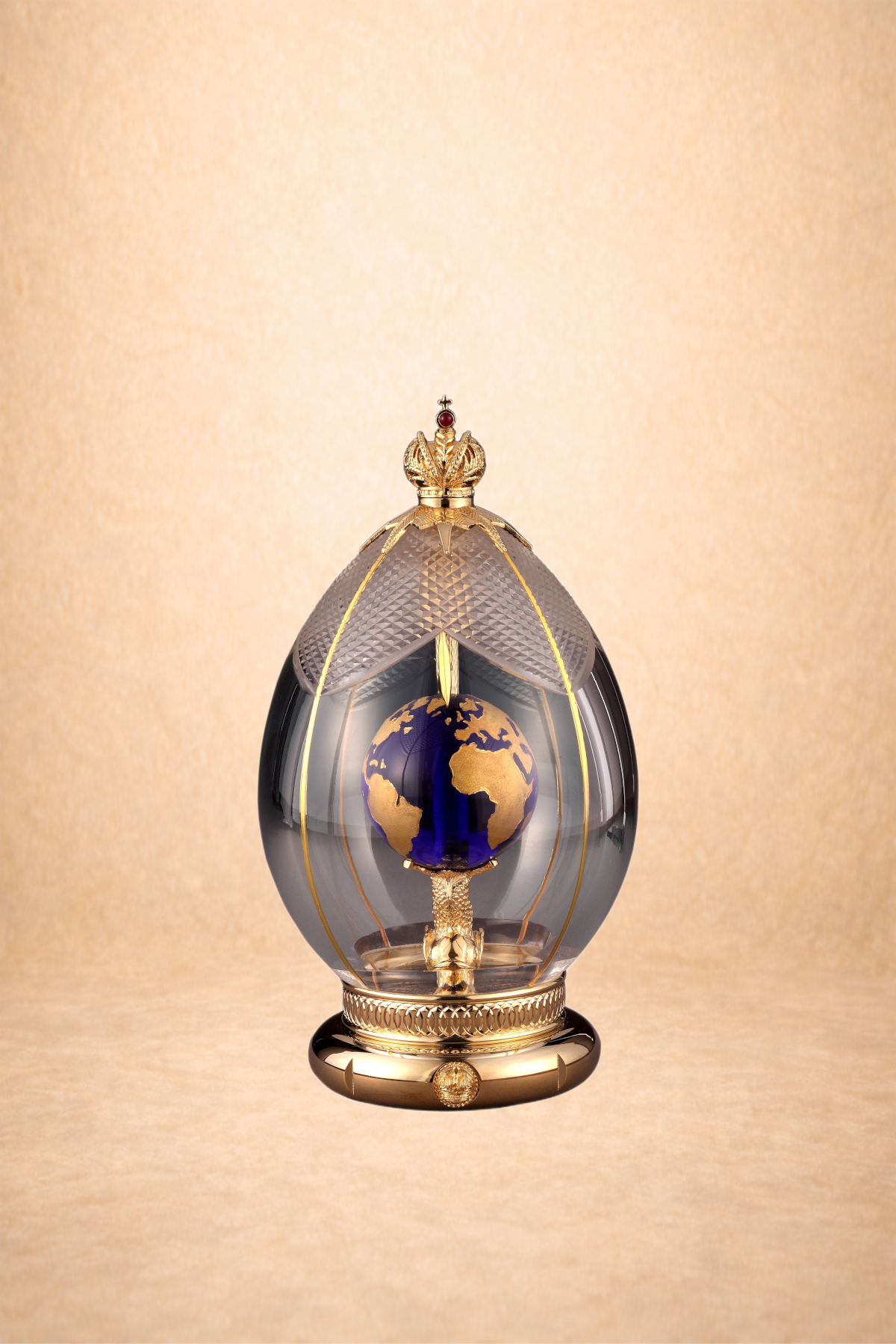 Luxurious decorative perfume bottle with gold accents, globe design, and crown ornament on top, set against a gold background.