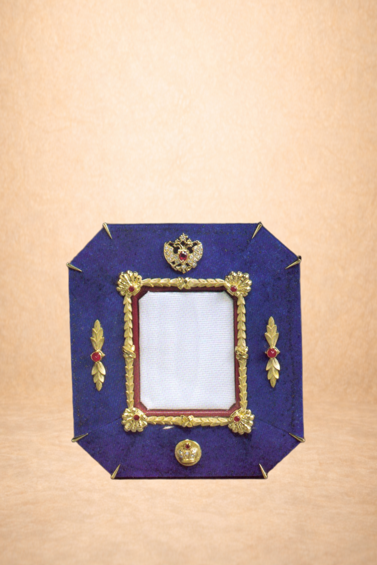Decorative belt with gold ornaments and red gemstones, displayed on a royal blue fabric background with gold pins.