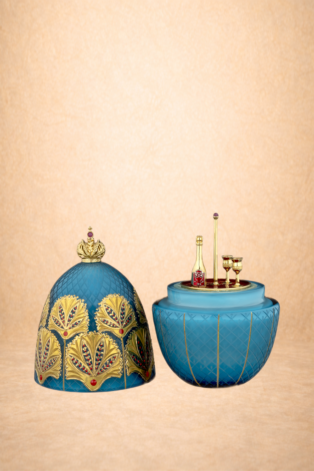 Violet perfume bottle with a gold crown cap and decorative gold leaf design, and a blue container with a gold quilted pattern holding mini bottles and glasses, set against a beige background.