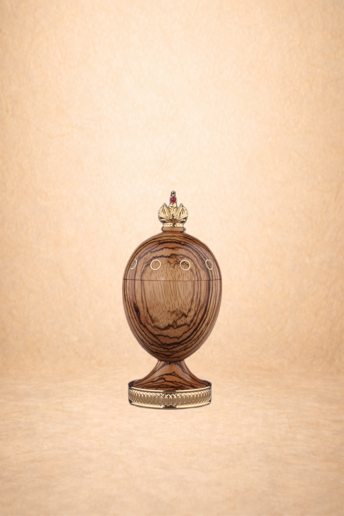A wooden egg-shaped object with circular gold accents, topped with a crown and placed on a decorative golden base.