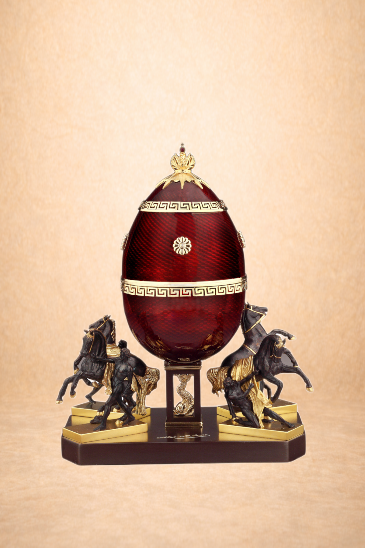 Decorative table with a large red egg-shaped ornament, gold accents, and horse sculptures on a black and gold base against a beige background.