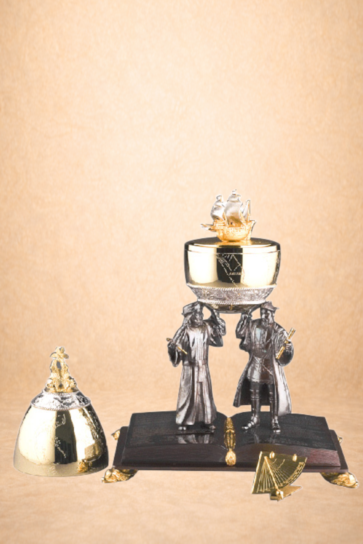 Decorative trophies resembling small statues of sailors and a barrel, placed on a black platform with a beige background.