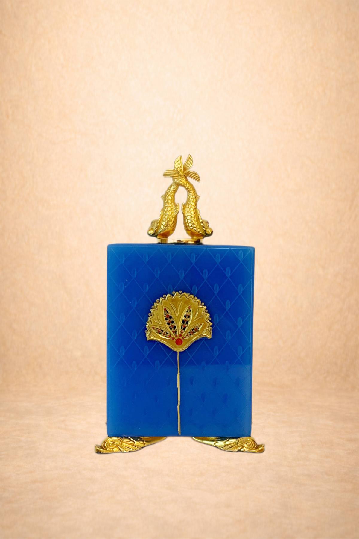 A decorative blue box with gold embellishments, topped with two gold fish-shaped ornaments and standing on gold feet.