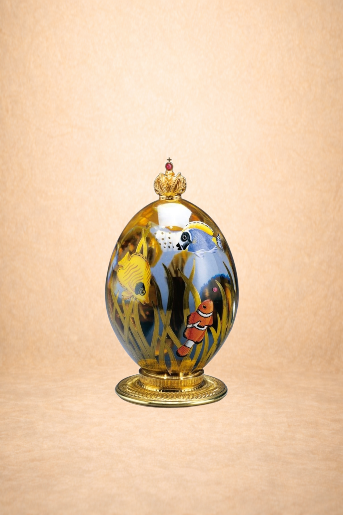 Decorative glass egg with painted tropical fish and seaweed, topped with a gold crown and set on a gold base.