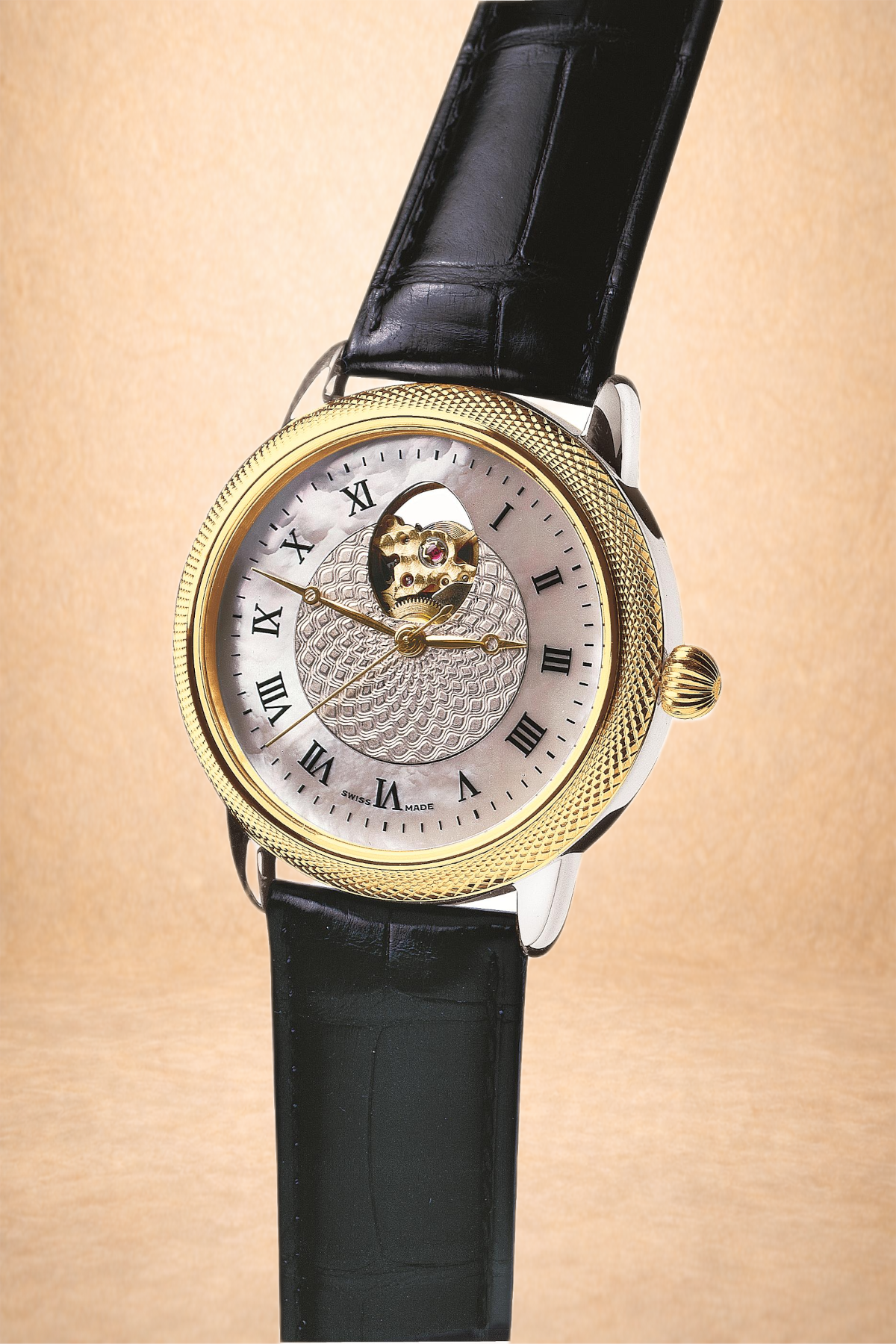 A luxury wristwatch with a black leather strap, gold bezel, and a silver face featuring Roman numerals and an open heart display showing the watch's inner mechanism.