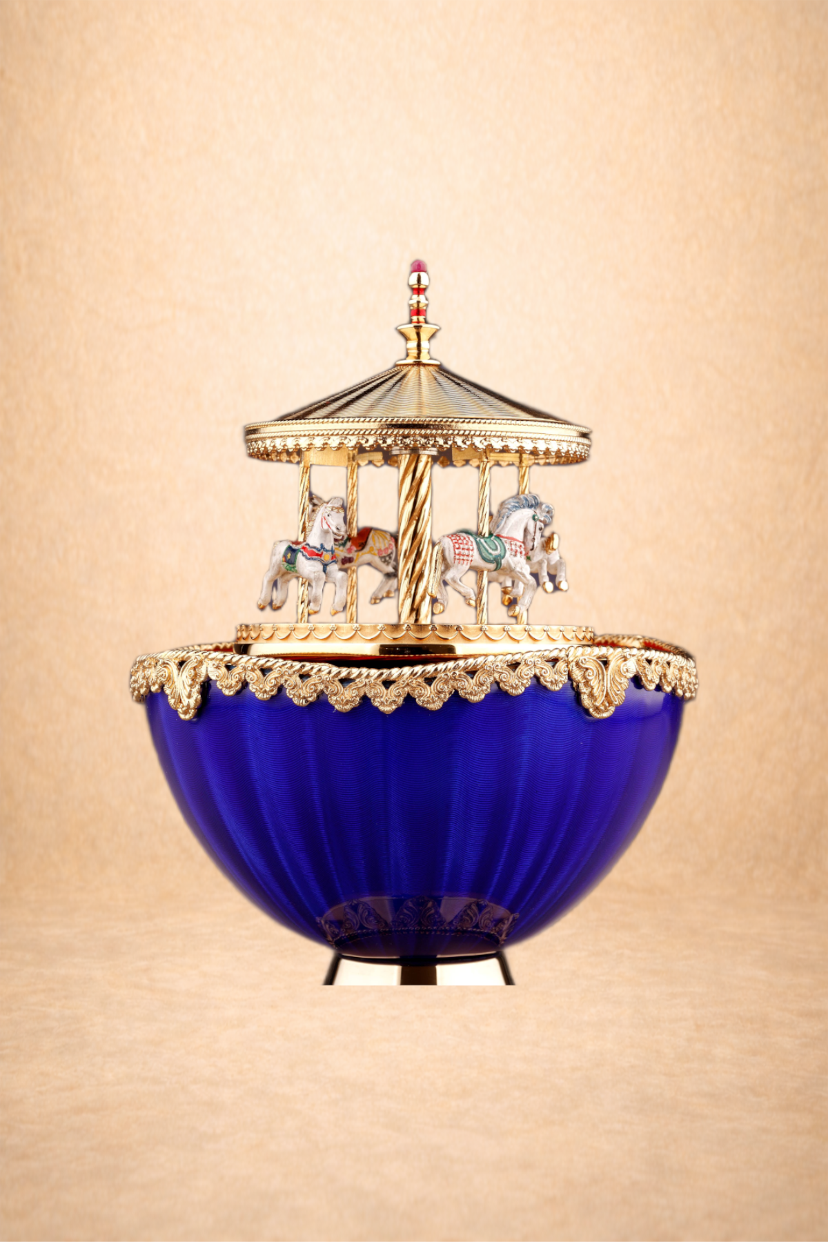 A decorative vintage music box with a bright blue base and gold detailing. The top features a miniature carousel with painted horses and a gold canopy.