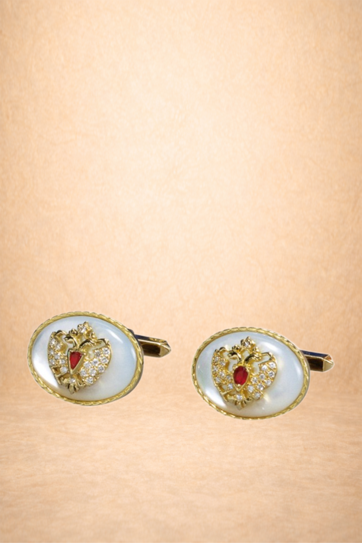 Gold and pearl cufflinks with a lion crest and red gemstone accents on a beige background.