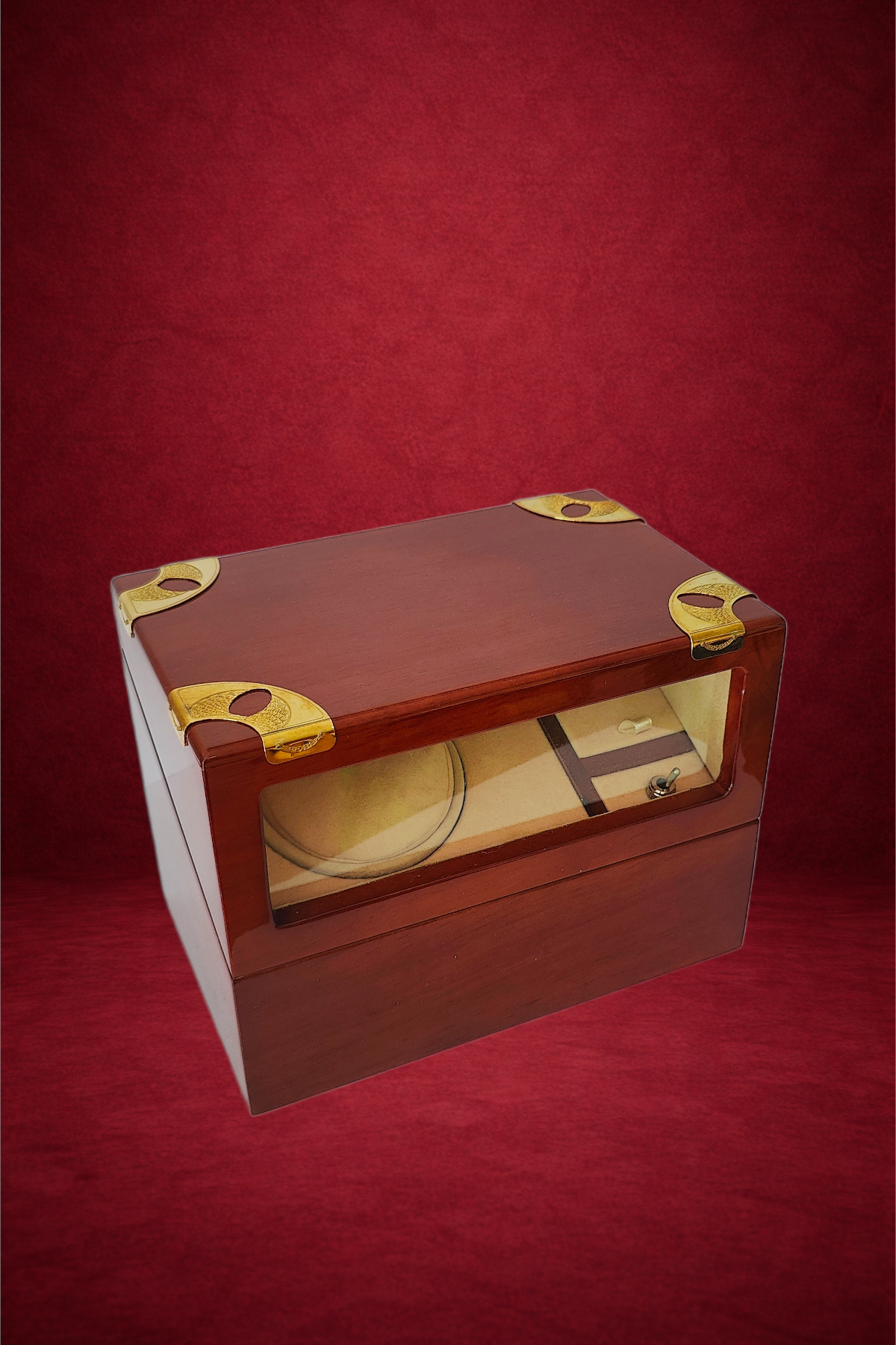 A vintage wooden cigar humidor box with glass top and gold accents on a red background.