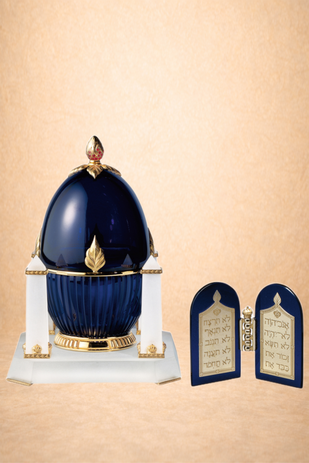 A decorative blue and gold Jewish ceremonial ark with a decorative lid, and an open blue and gold prayer tablet with Hebrew text.