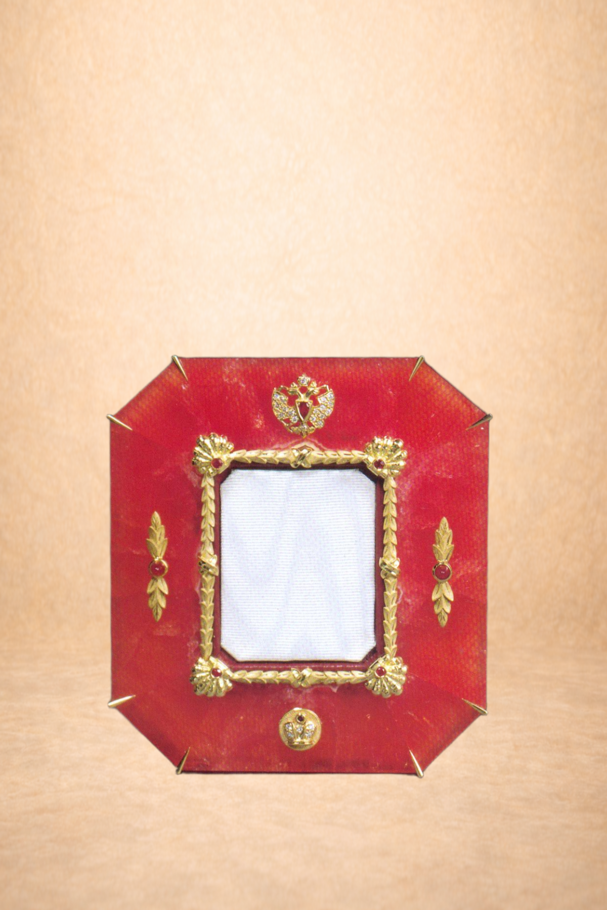 A decorative ornate picture frame with gold accents on a red background, placed on a beige surface.