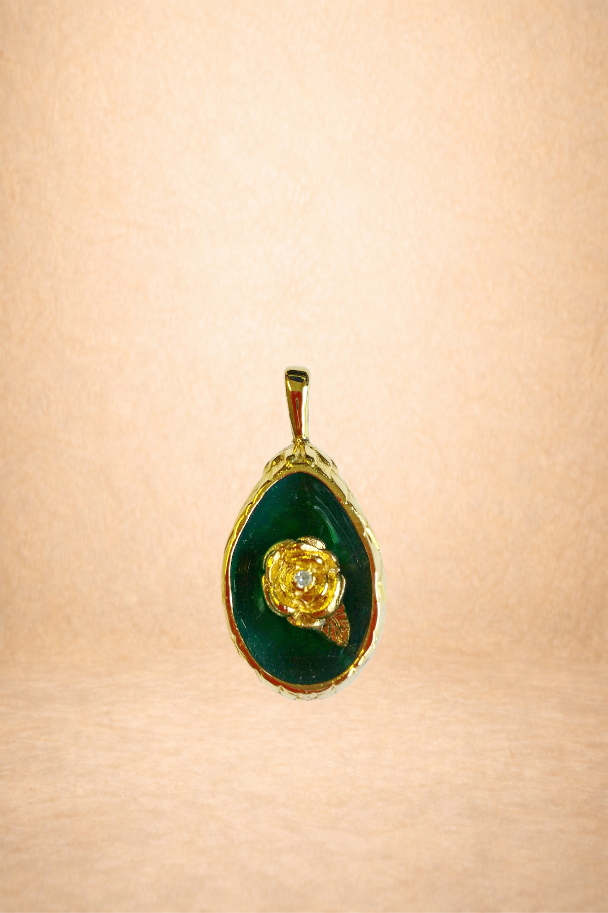 Gold pendant with green background and a gold rose design inside.