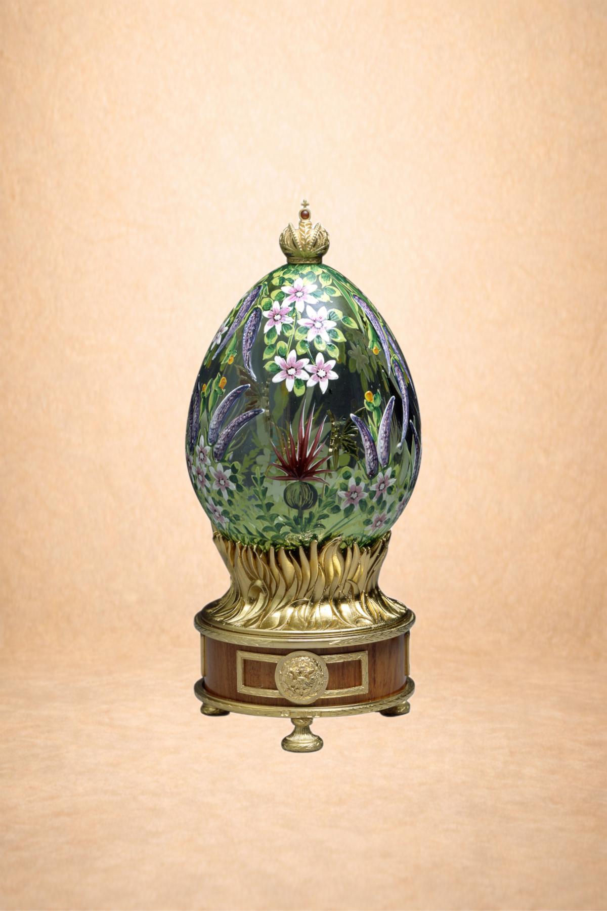 Decorative glass egg with floral design on a wooden and gold stand.