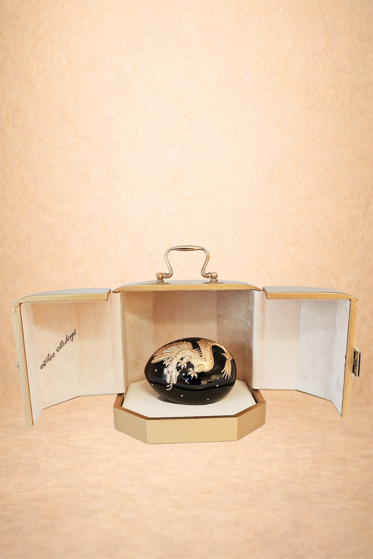 A black jewelry box with a gold decorative fish design inside a beige case, displayed against a plain background.