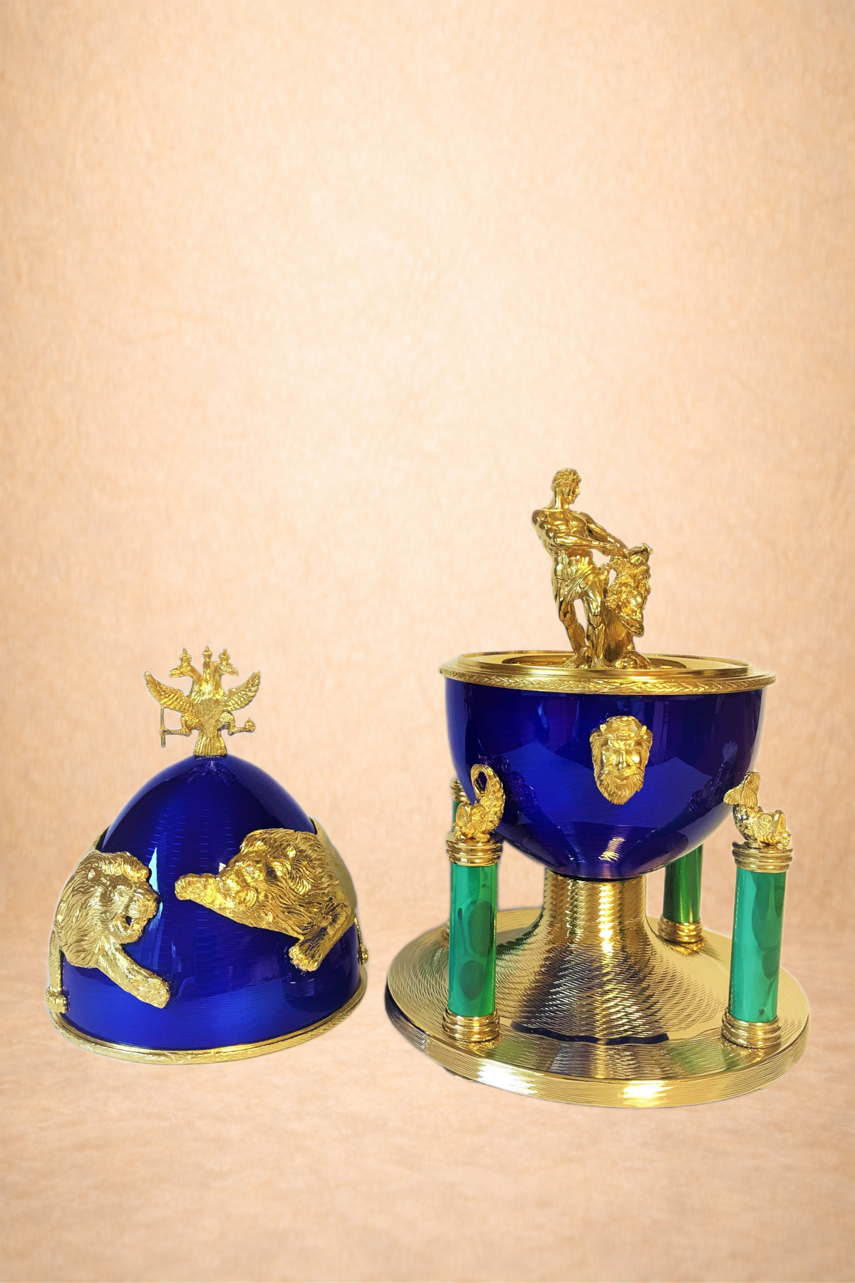 A set of two decorative blue and gold objects with lion and eagle motifs, one shaped like a helmet and the other like a bowl or container with a figurine on top.