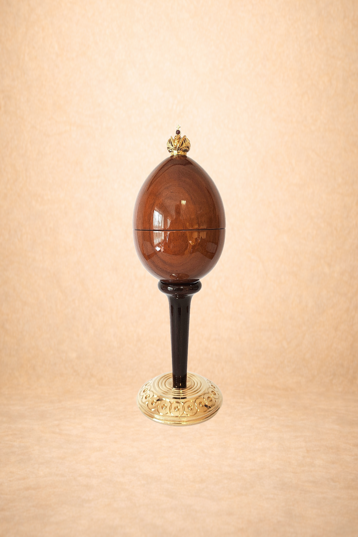 Decorative object resembling an ornate egg with a golden crown on top, mounted on a stand with a detailed base.