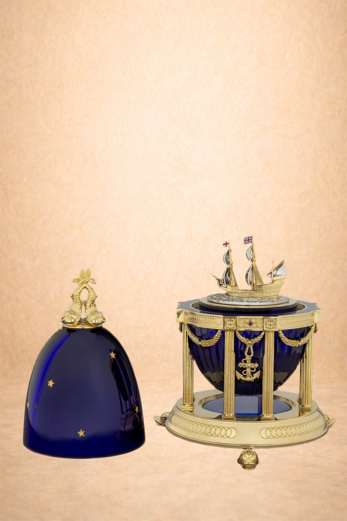 A decorative navy blue and gold ship model with gold accents and a matching dome-shaped cover with stars.