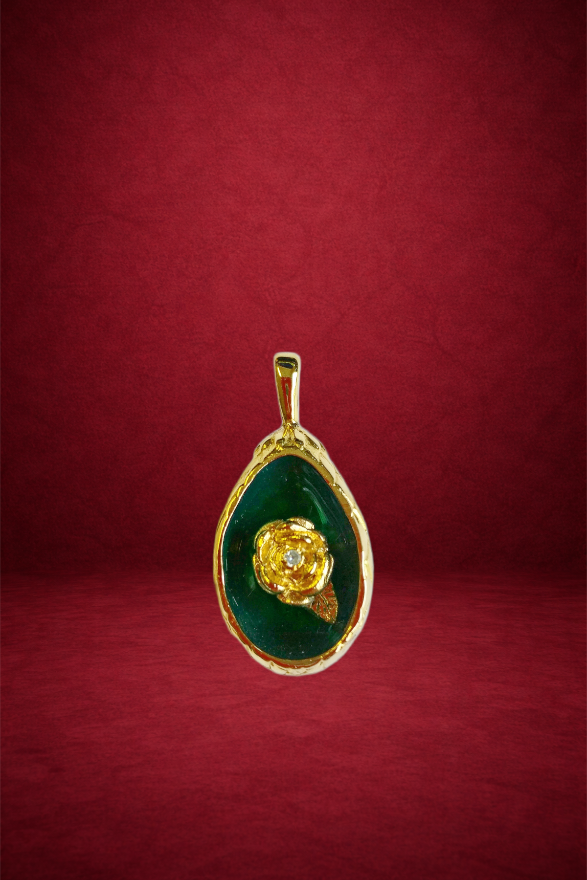 Gold pendant with a green background featuring a gold rose and leaf design.