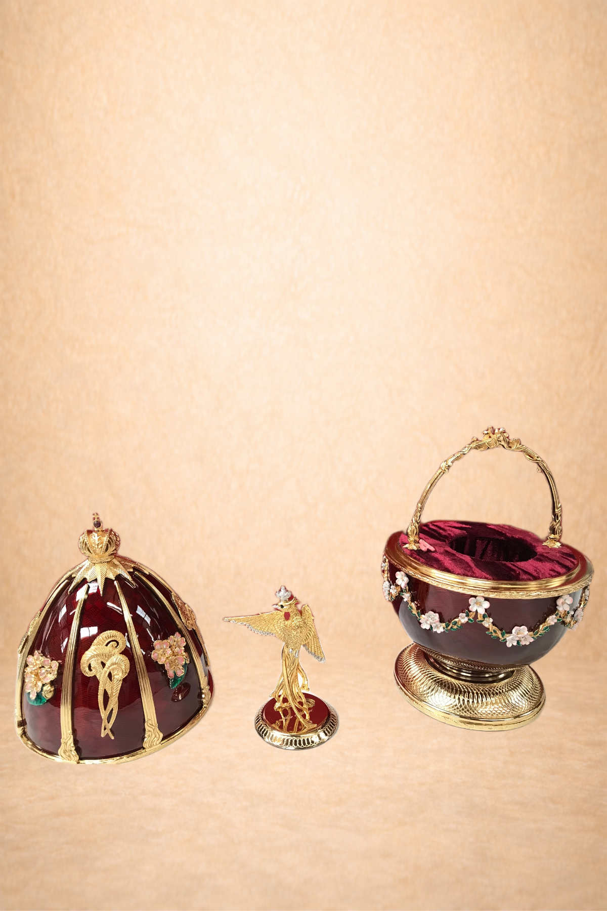 Three ornate jewelry boxes, likely designed to resemble a crown, a hummingbird, and a bowl, decorated with gold, pearls, and floral motifs, set against a gold background.