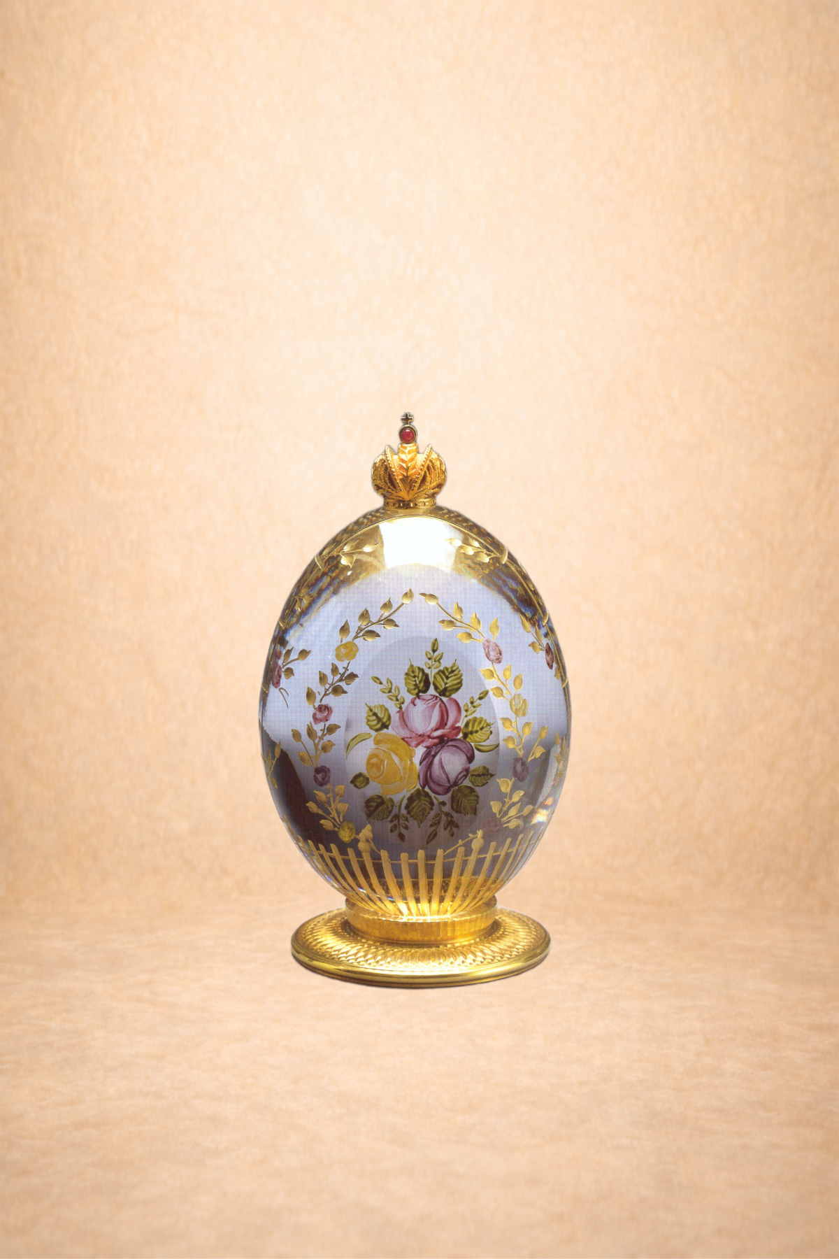 Decorative porcelain egg with floral design and gold accents, topped with a crown, on a gold stand, against a beige background.
