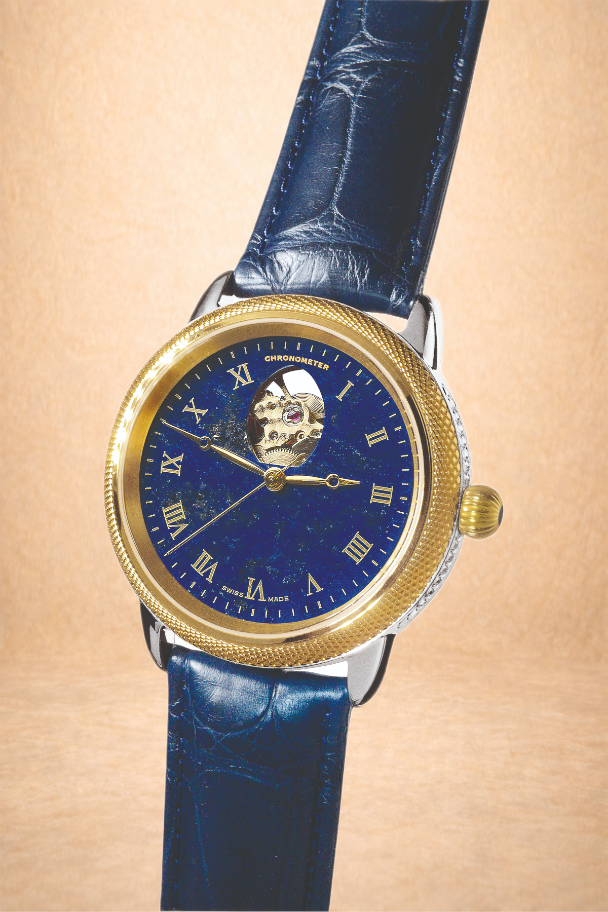 A luxury wristwatch with a blue leather strap, gold bezel, and an open-heart dial showing the movement. The dial is dark blue with Roman numerals, and the time is approximately 3:53.