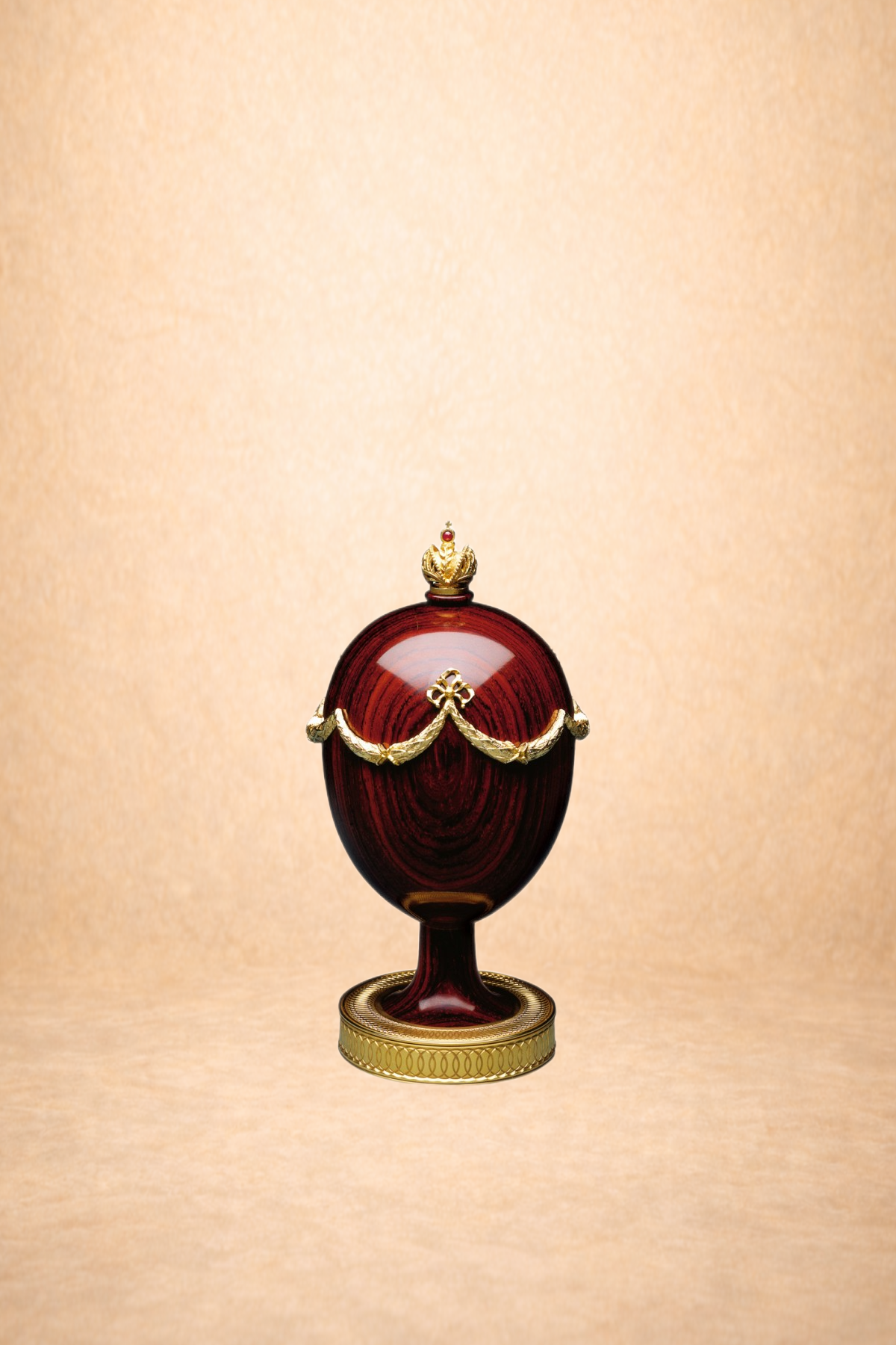 A decorative egg-shaped object with a red and purple woodgrain pattern, adorned with gold embellishments and a crown on top, standing on a gold stand.