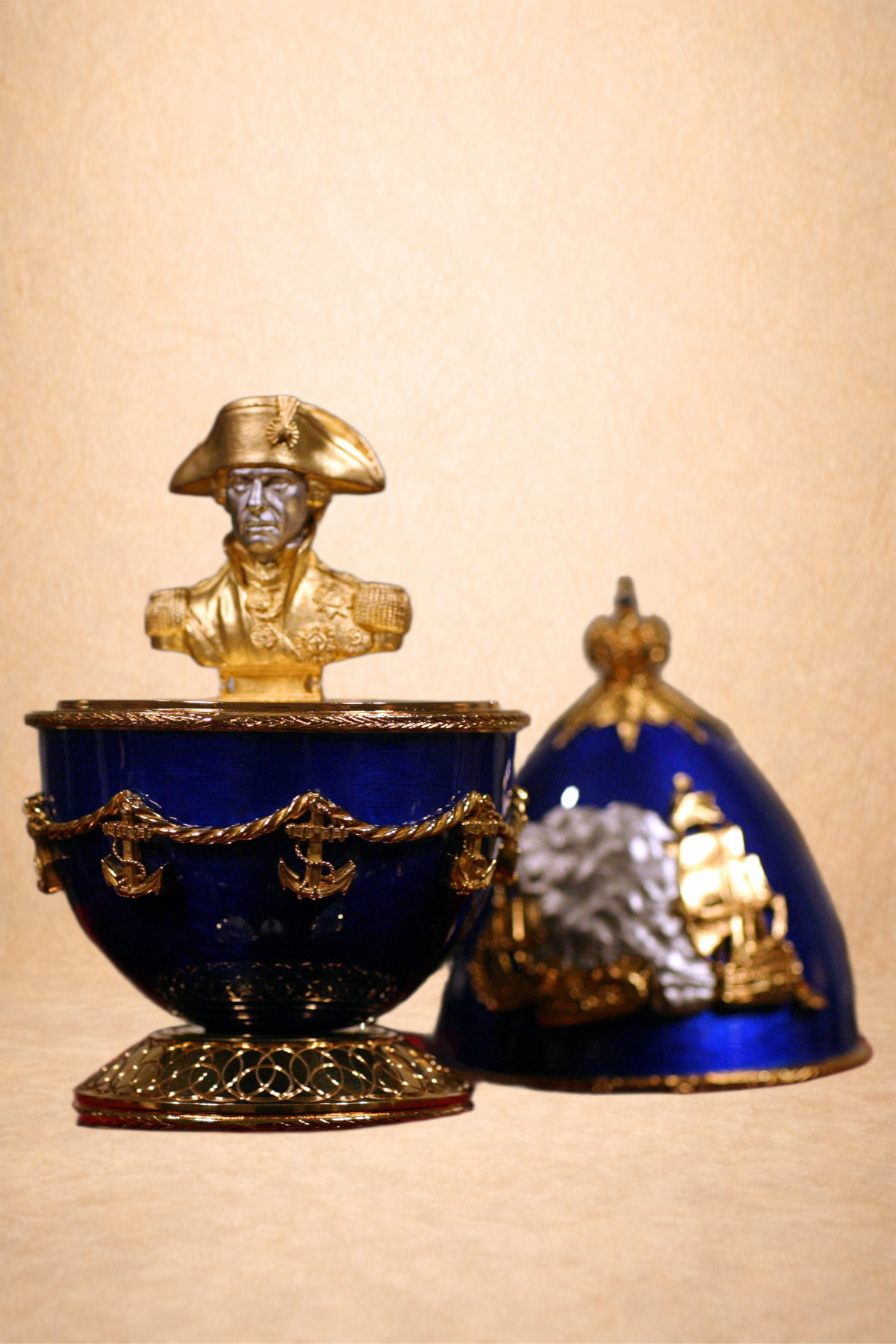 Decorative display with a bust of a military figure, a blue and gold military-style hat, and a blue container with gold accents and anchor motifs.