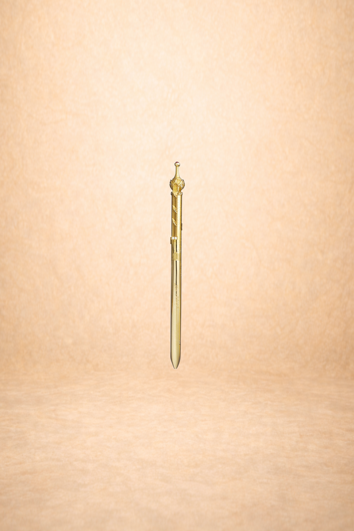 A medieval-style dagger with a gold-colored hilt and detailed design, set against a plain, light orange background.