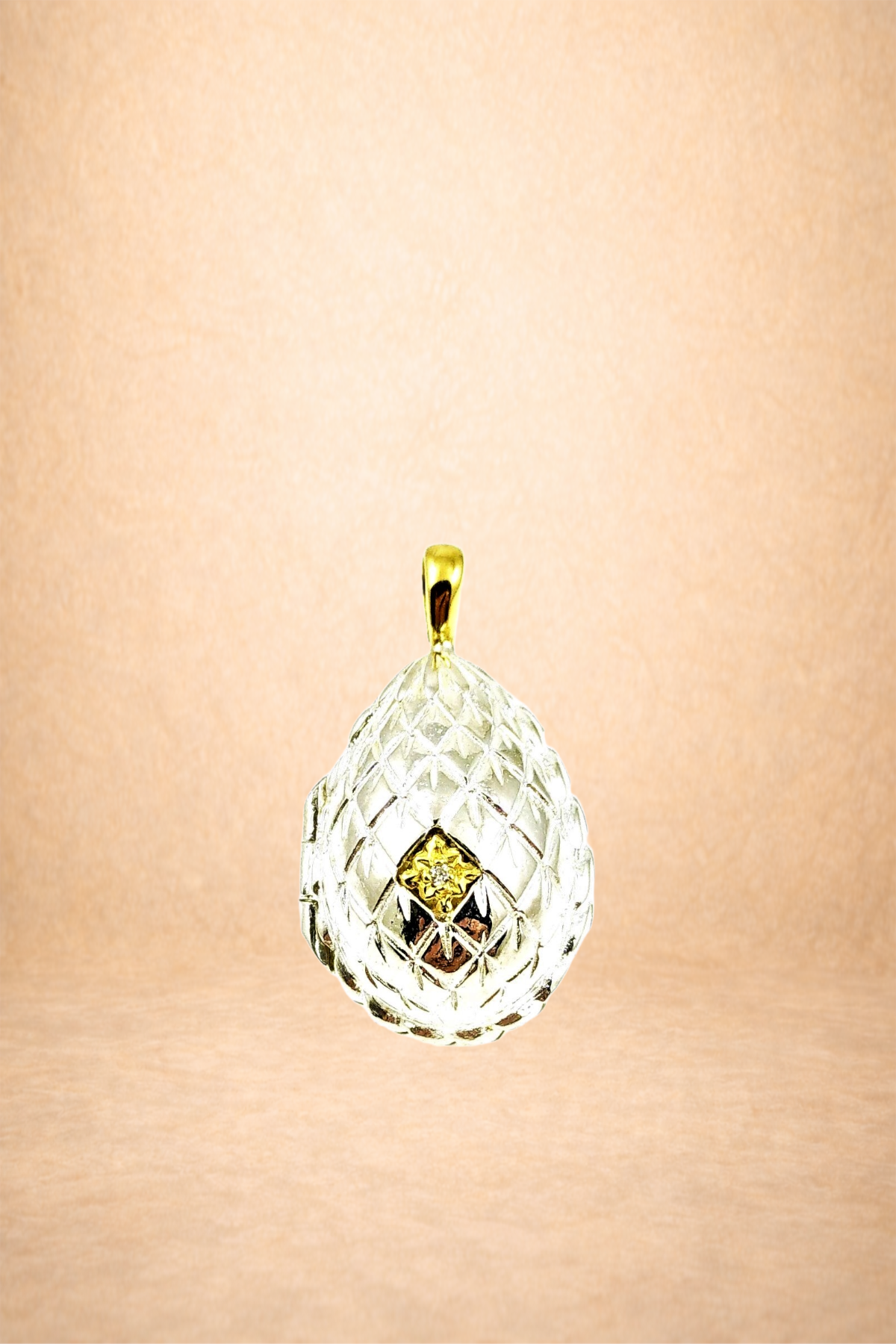 A diamond pendant jewelry hanging against a light peach background.