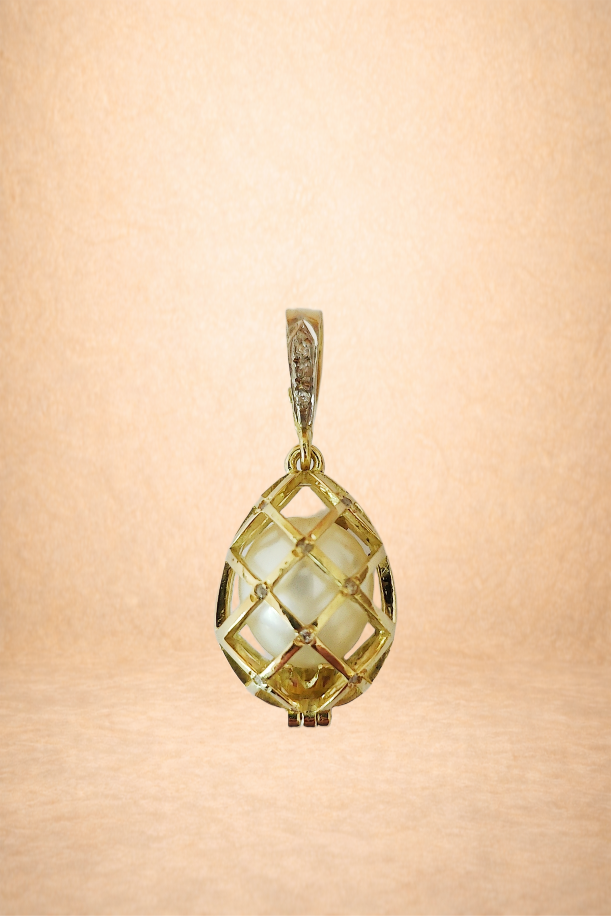 Gold pendant with white pearls inside a geometric grid design hanging against a light peach background.