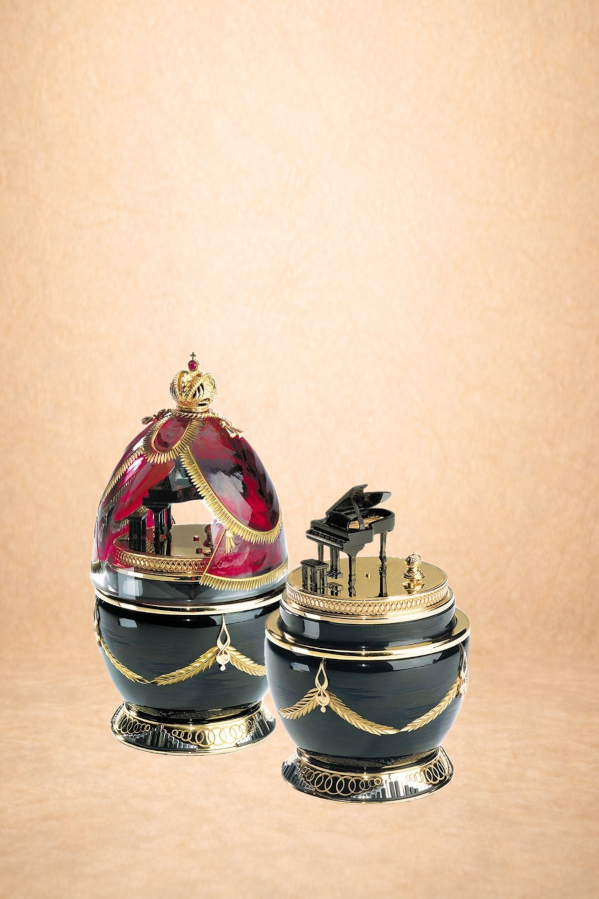 Two ornate decorative music box globes with black bases, gold detailing, and miniature piano and crown ornaments, set against a beige background.