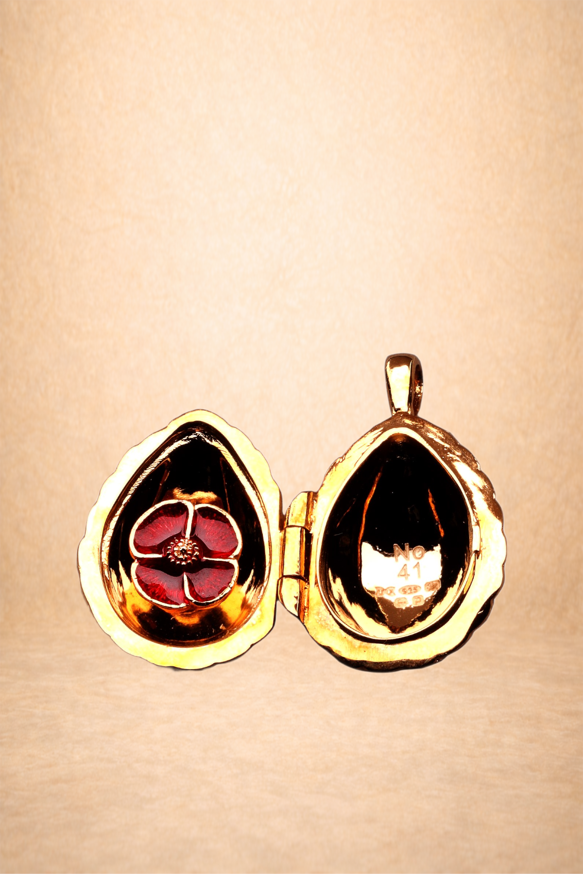 Gold locket open revealing red and black floral design inside.