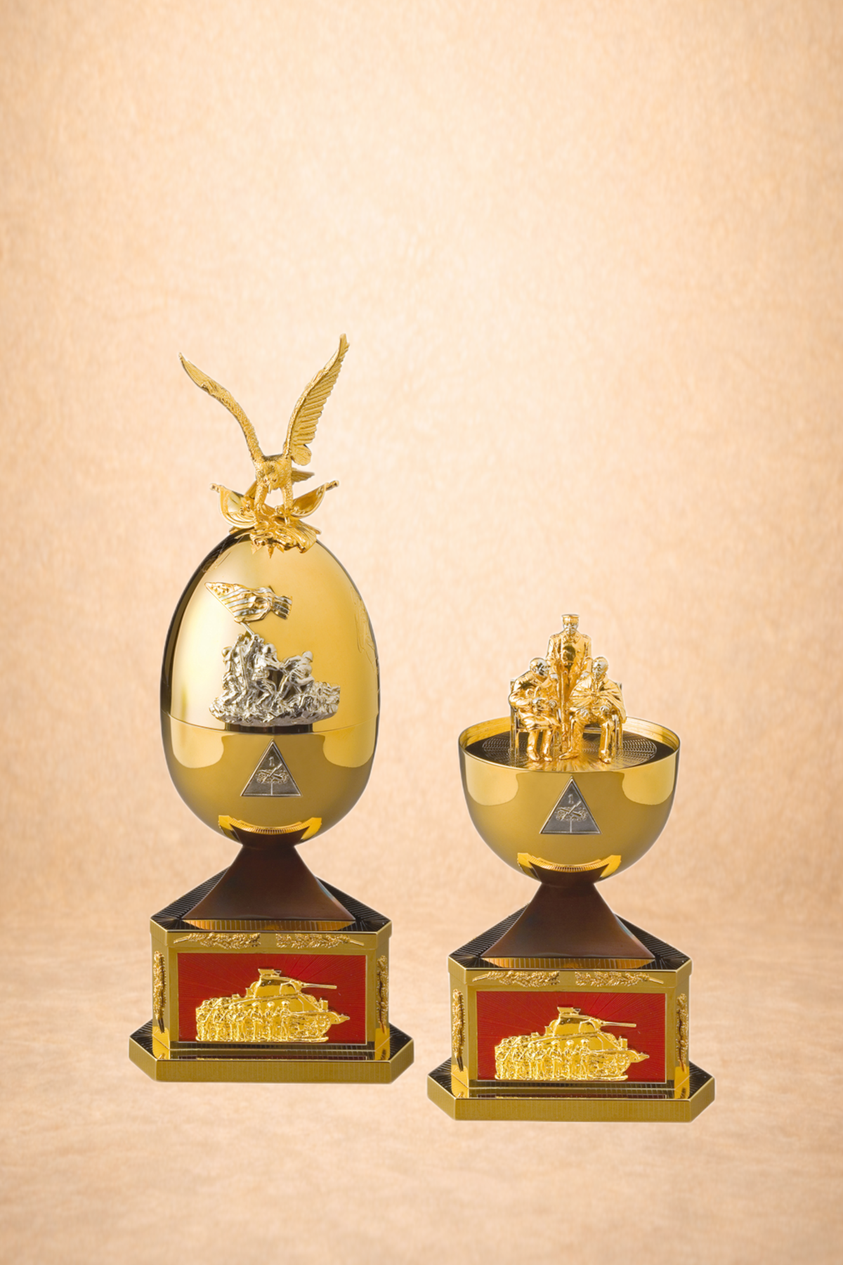 Two gold and black trophies with military-themed designs on their bases, featuring war scenes and soldiers, set against a neutral beige background.