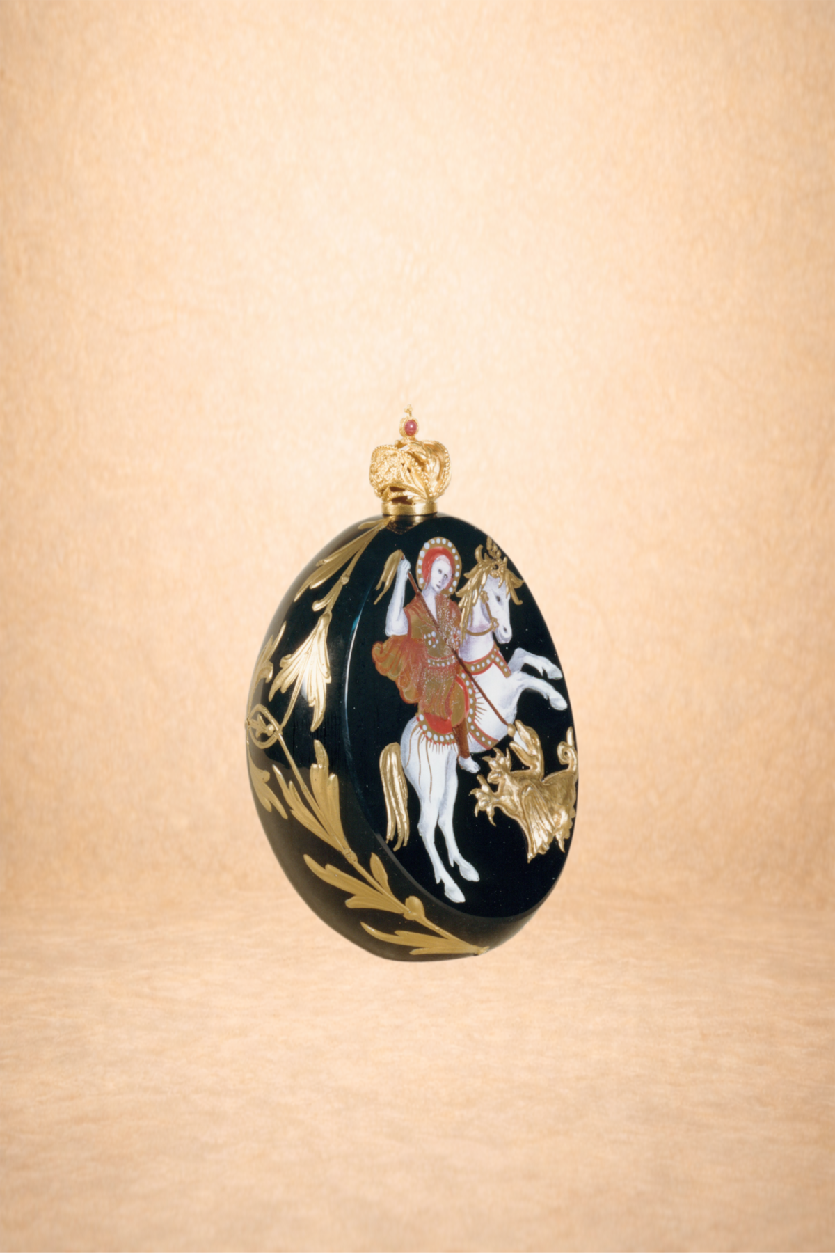 Decorative egg with an image of a person riding a horse, surrounded by gold accents and a crown on top.