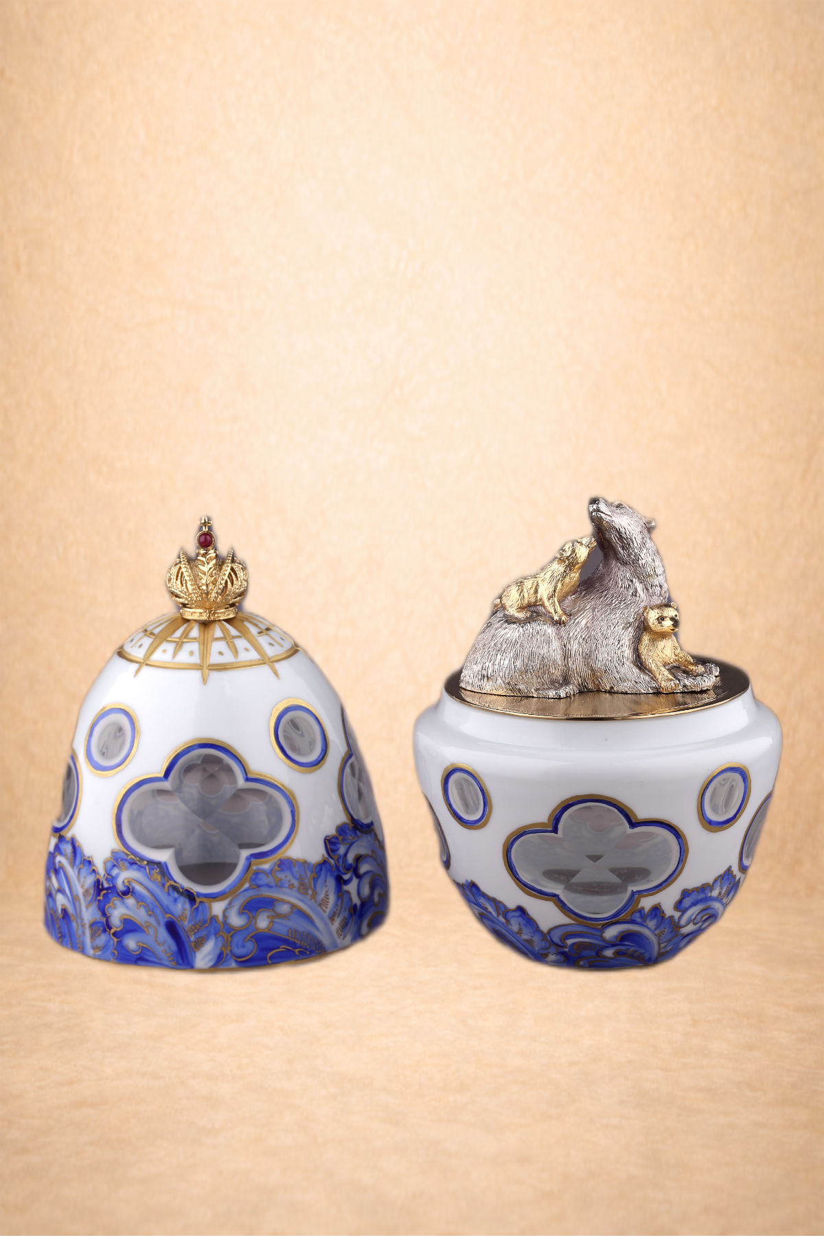 Decorative porcelain container set with blue and gold patterns, including one with a crown-shaped lid, and a second open container with a silver and gold animal sculpture of a bear, raccoon, and squirrel on top.